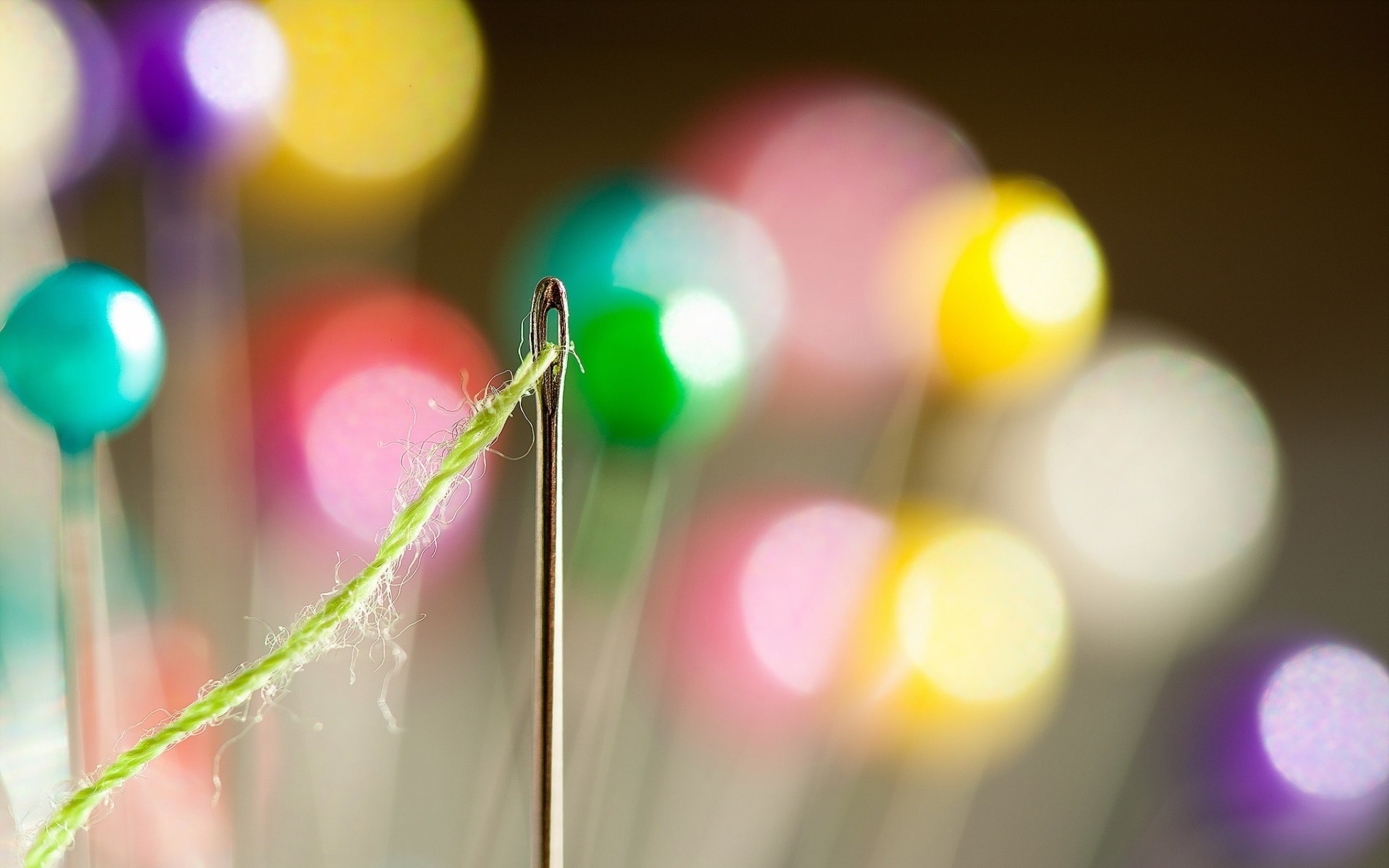 Macro photography of a needle and green thread with bokeh lights HD Wallpaper