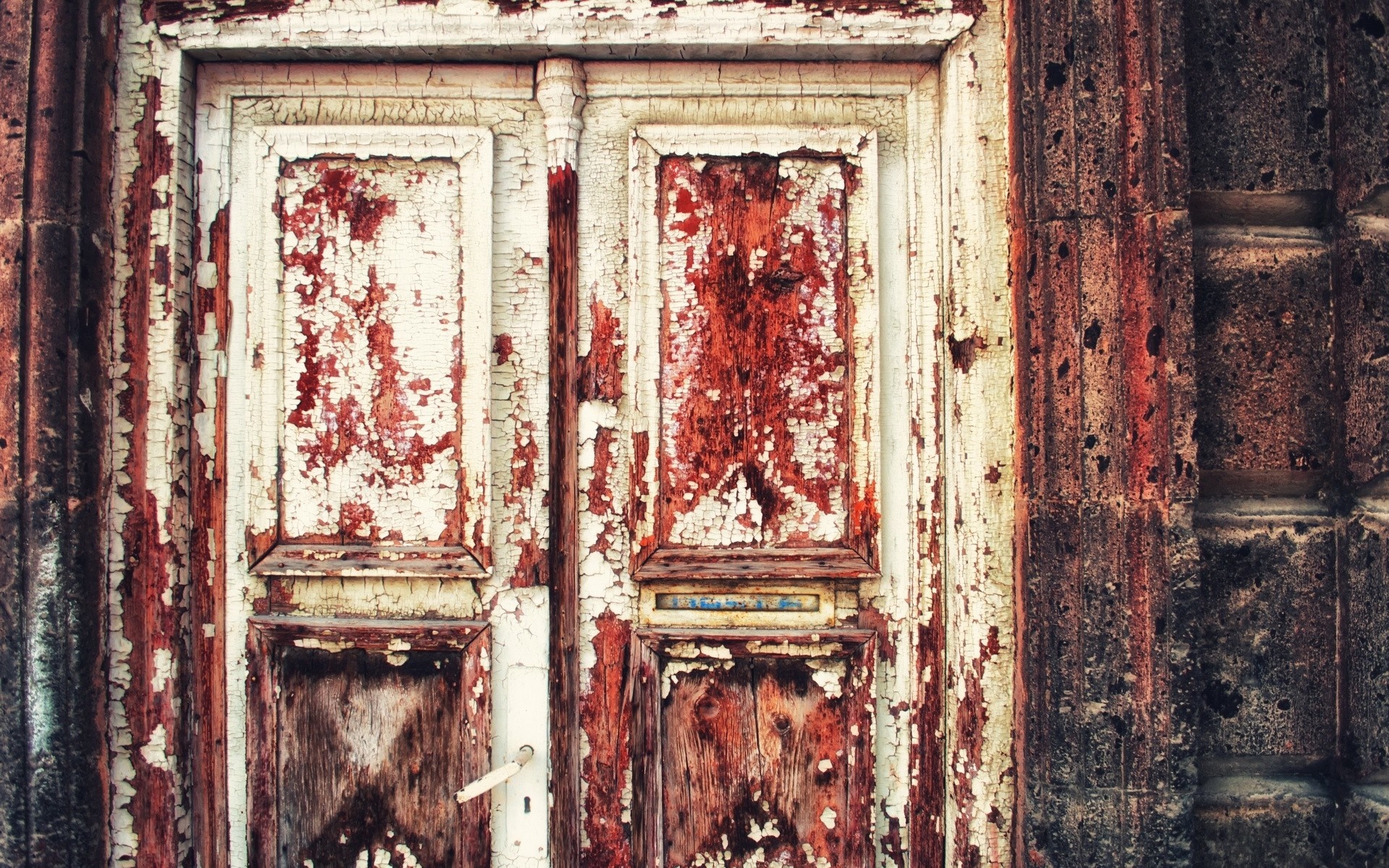 Peeling paint on an old wooden door with a stone wall HD Wallpaper