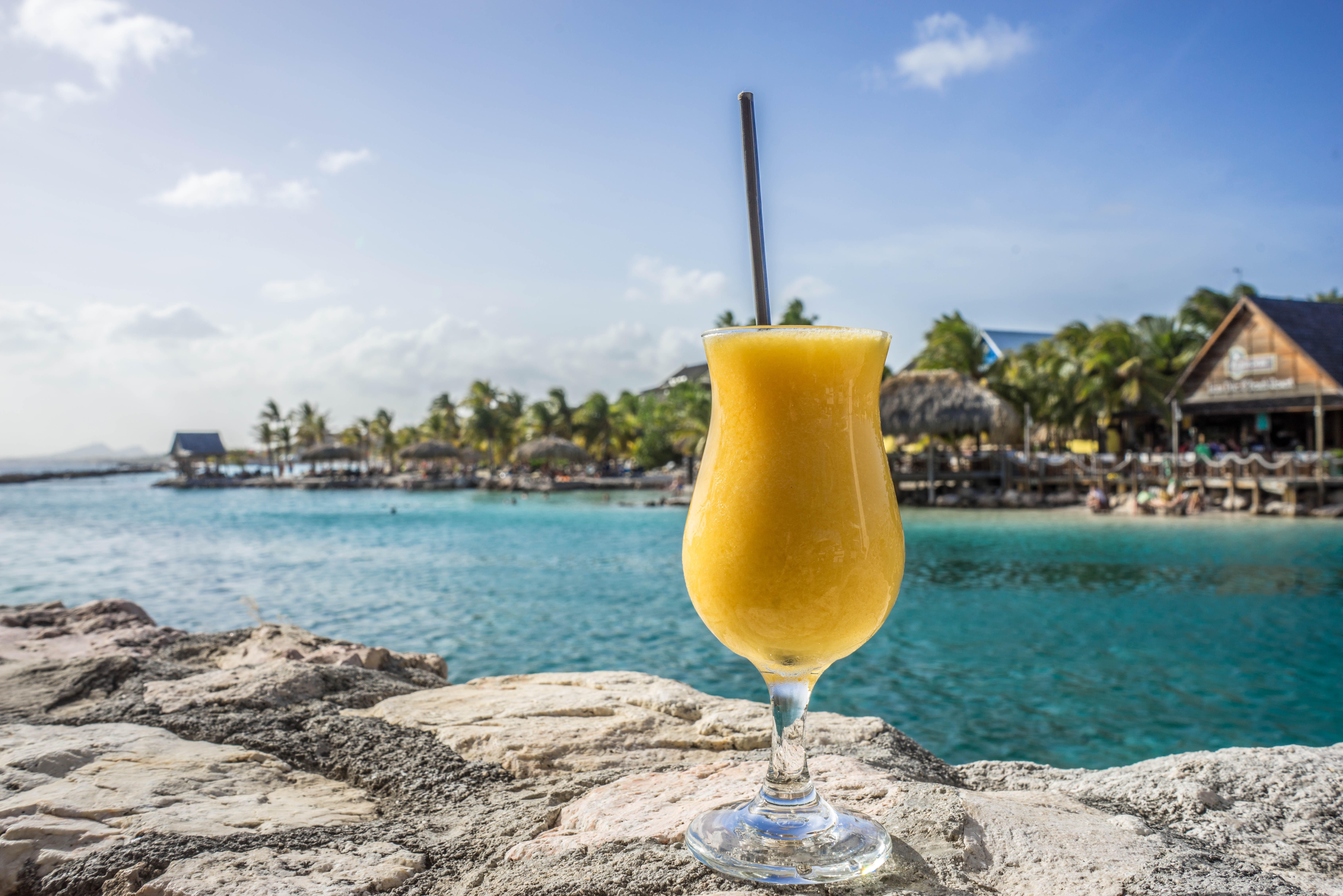 Yellow drink on rocks by the sea HD Wallpaper