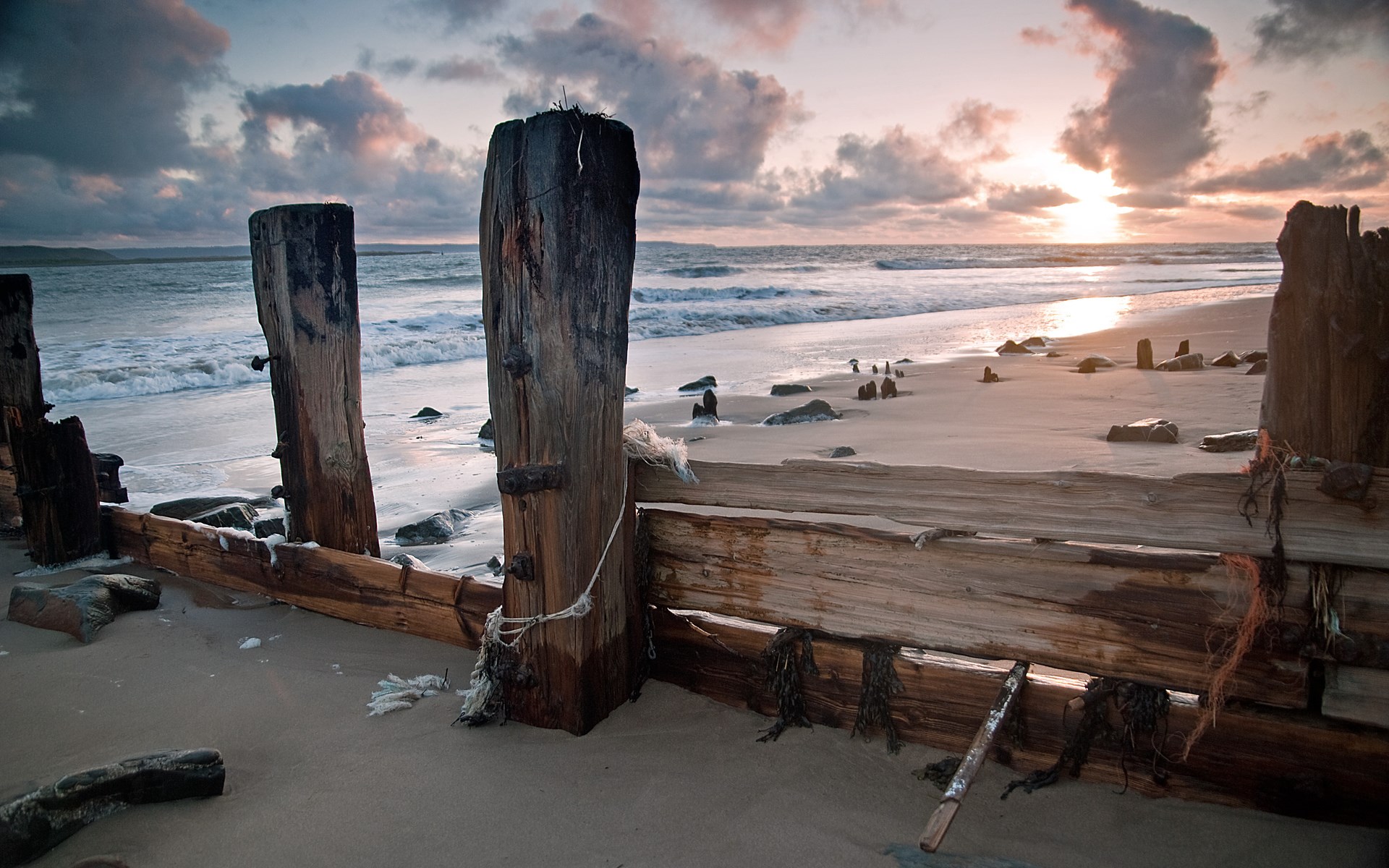 Wooden breakwater on a beach at sunset HD Wallpaper