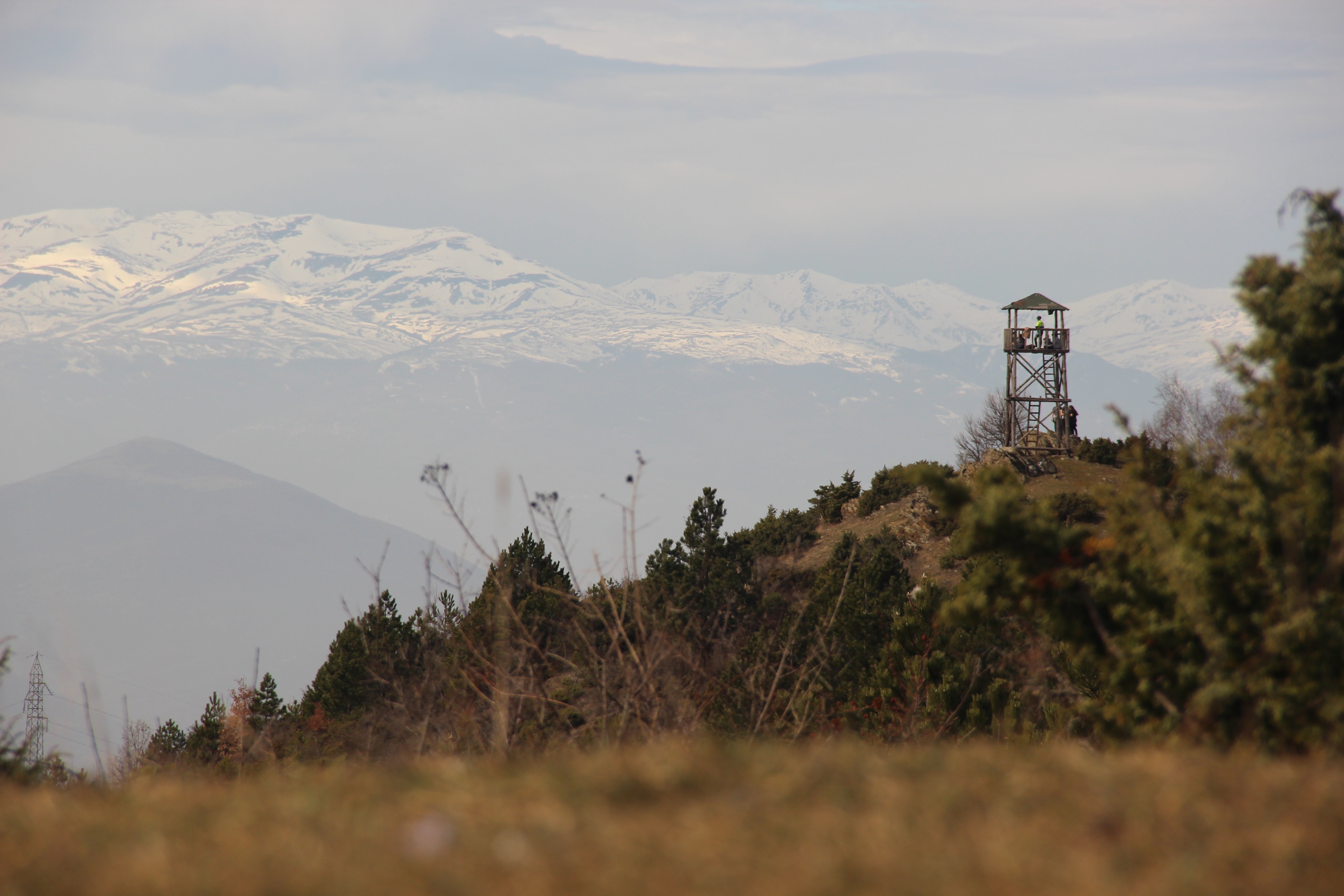 Watchtower on a hill with snow-capped mountains in the background HD Wallpaper