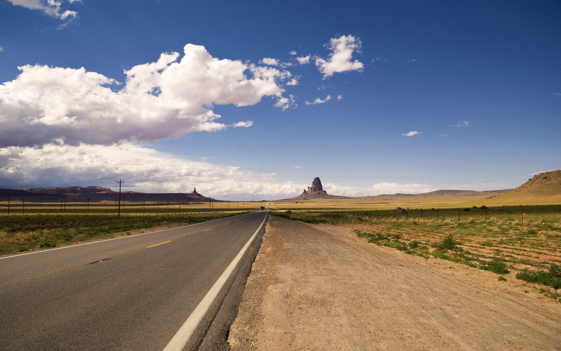 Desert road with mesas and clouds HD Wallpaper