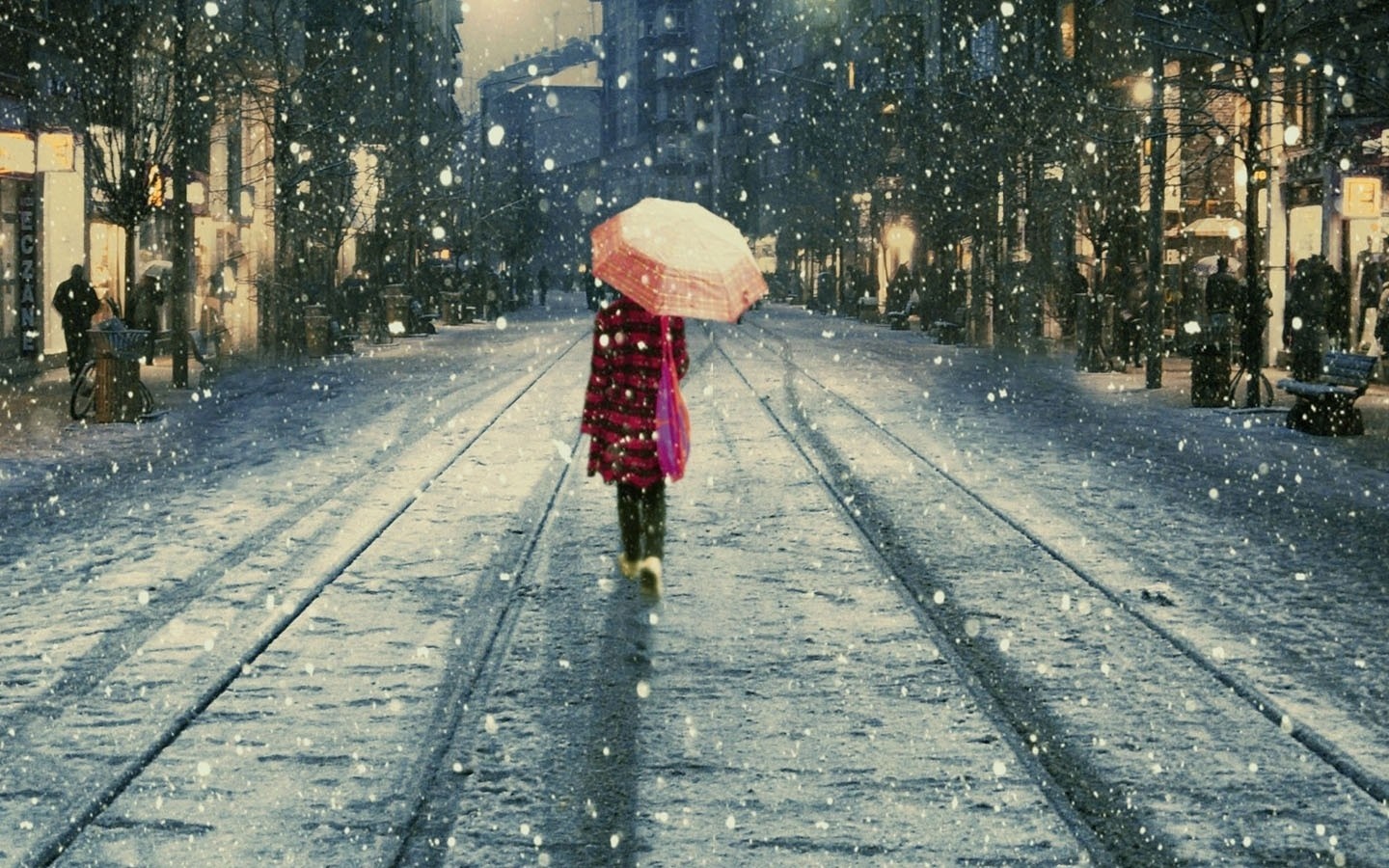Person with umbrella walking on snowy street with tram tracks HD Wallpaper
