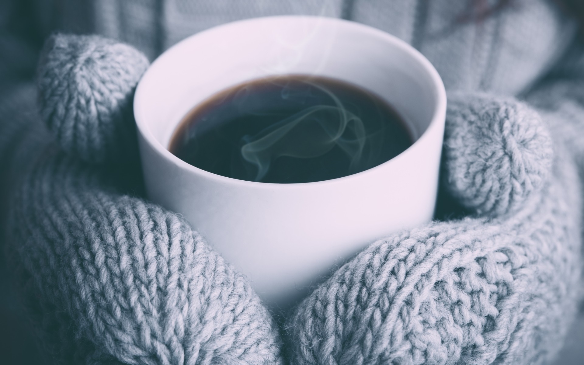 Close up of a steaming cup of coffee held by hands in knitted gloves HD Wallpaper