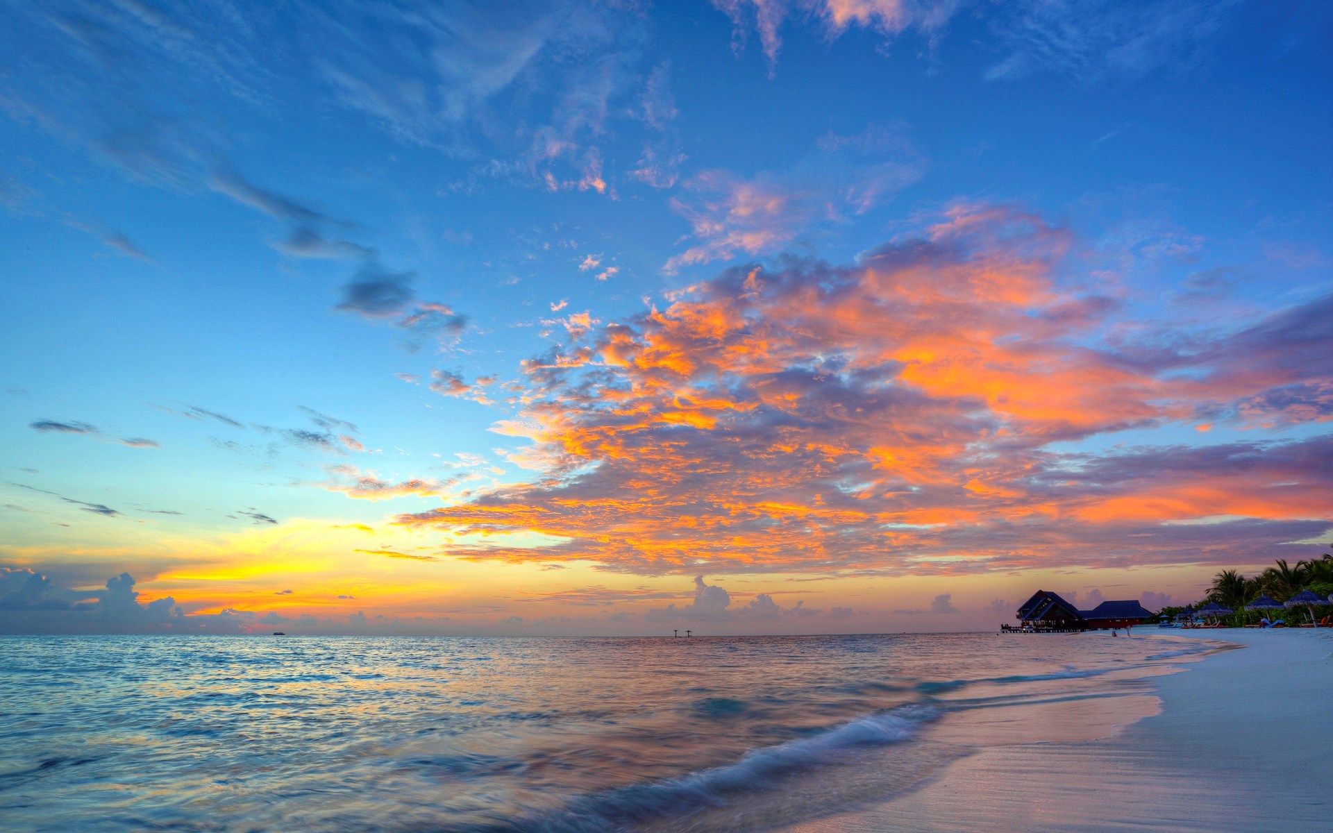 Sunset over a tropical beach with overwater bungalows HD Wallpaper
