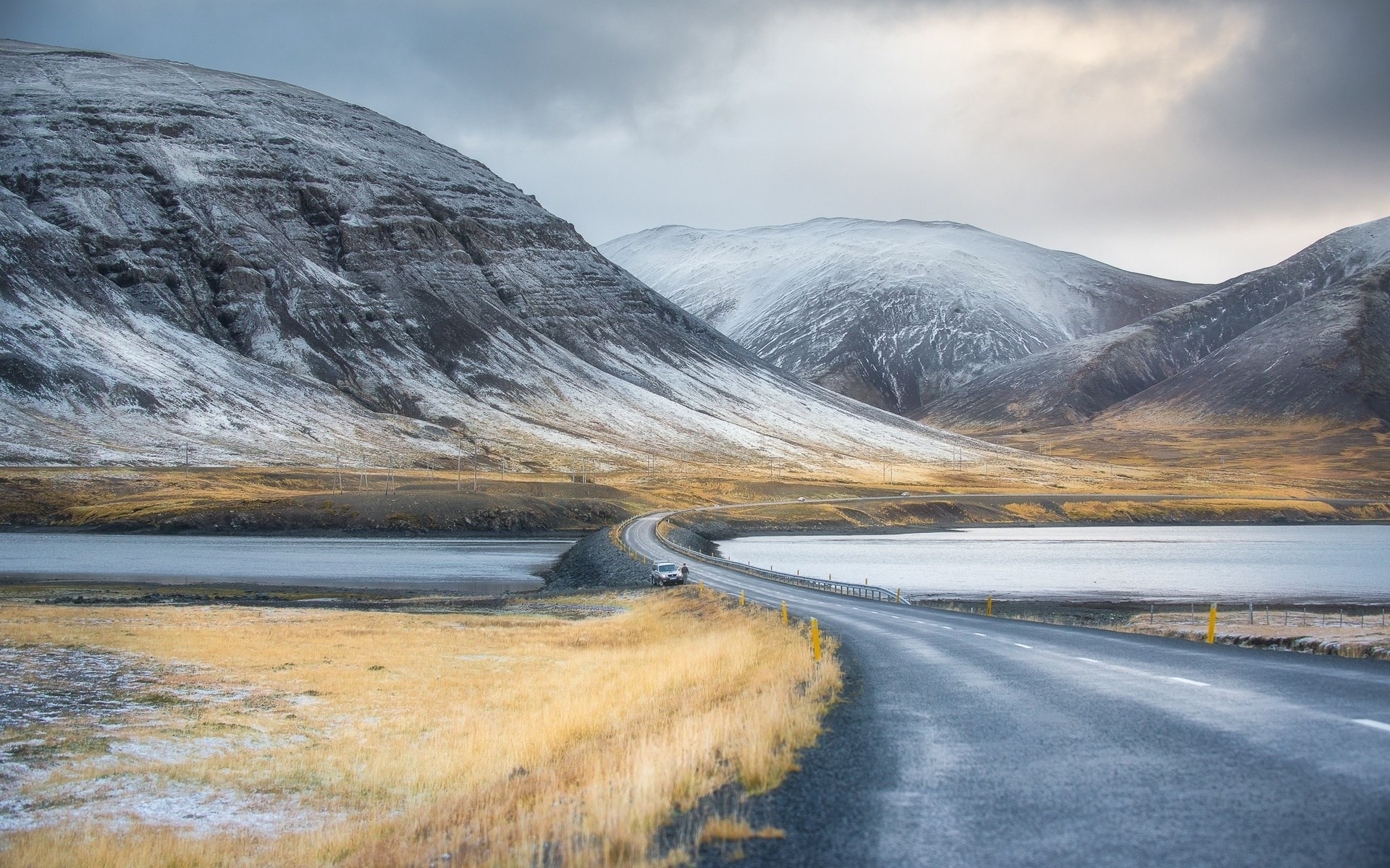 Car on a road in a snowy mountainous landscape HD Wallpaper