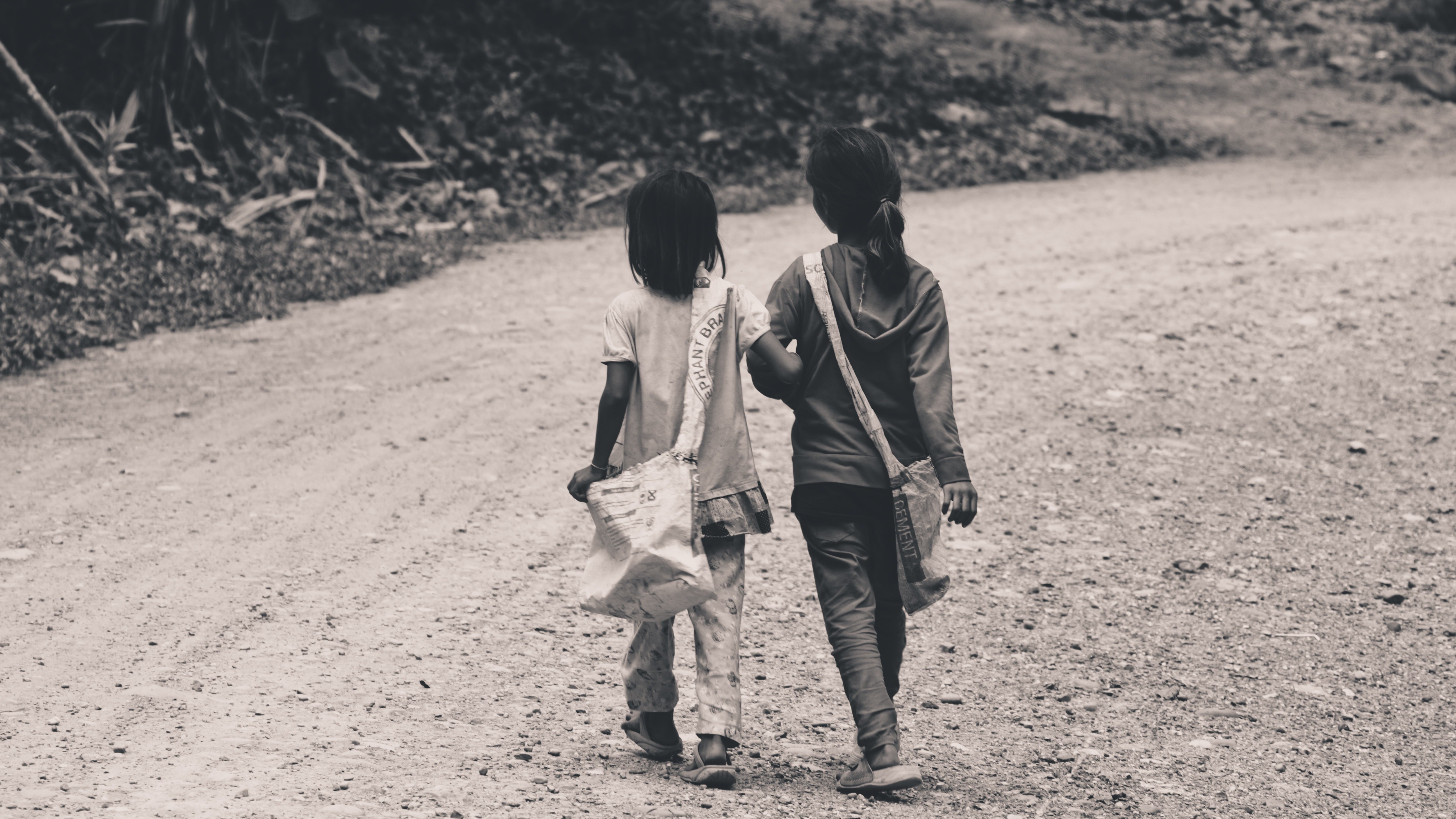 Two children walking on a dirt path HD Wallpaper