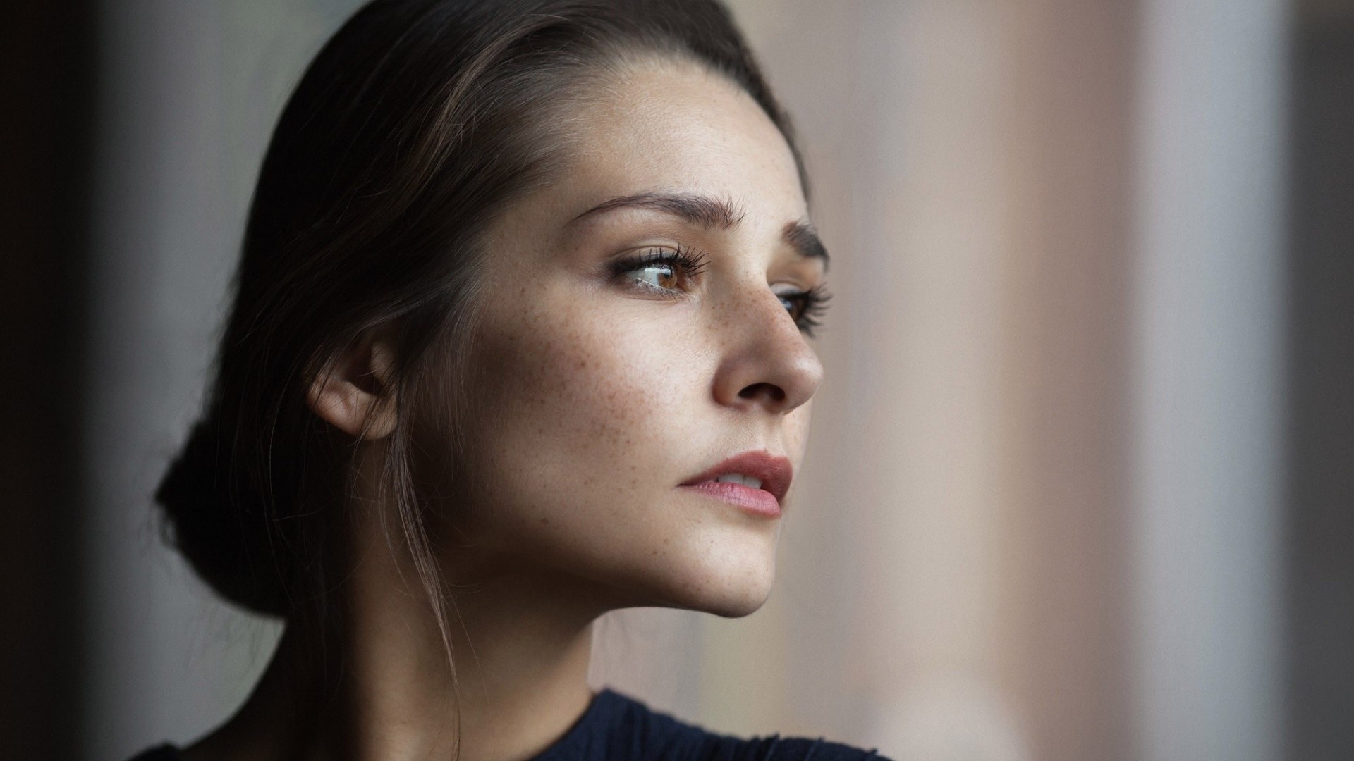 Woman with freckles looking to the side HD Wallpaper