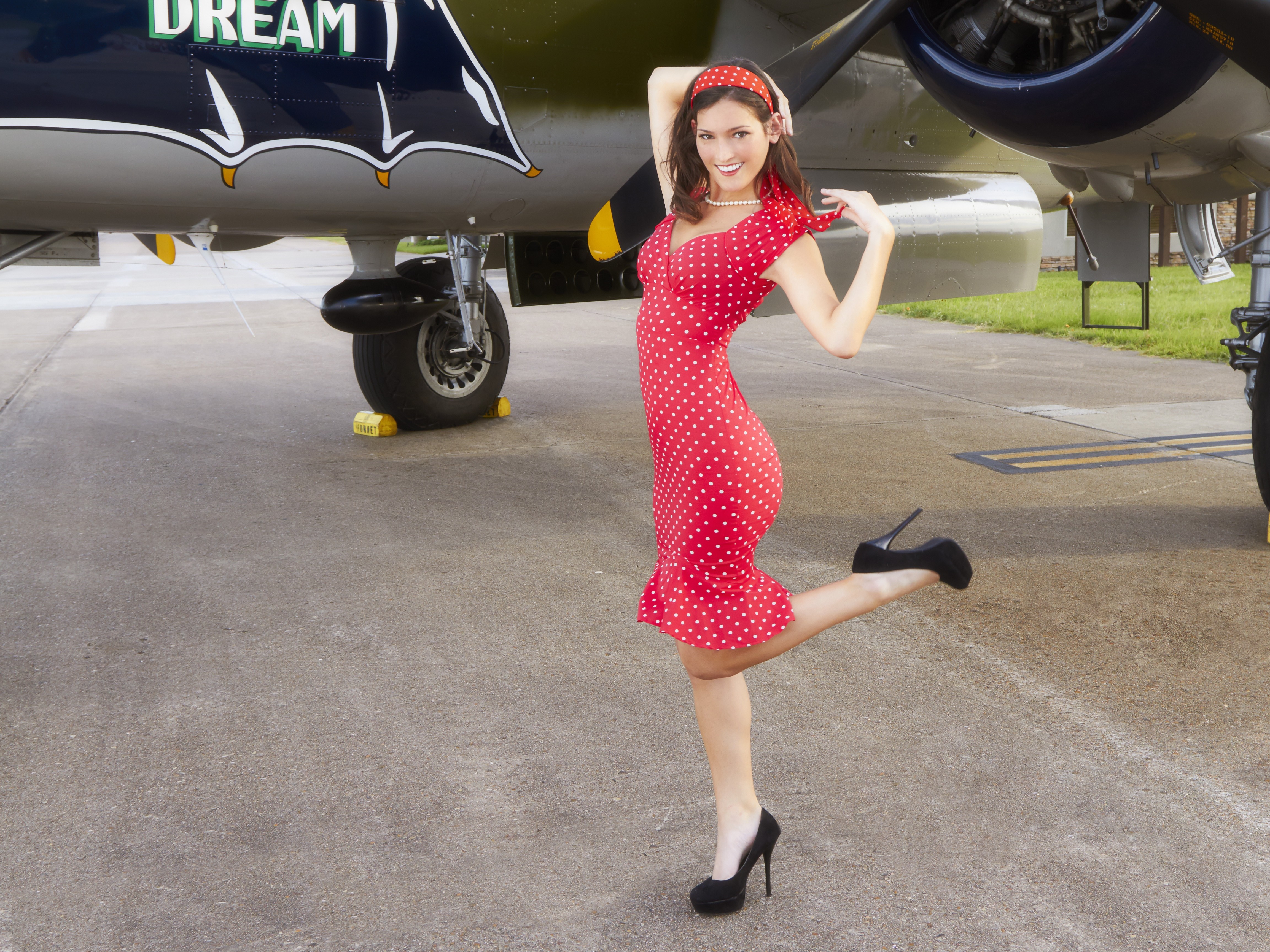 Woman in red polka dot dress posing by airplane HD Wallpaper