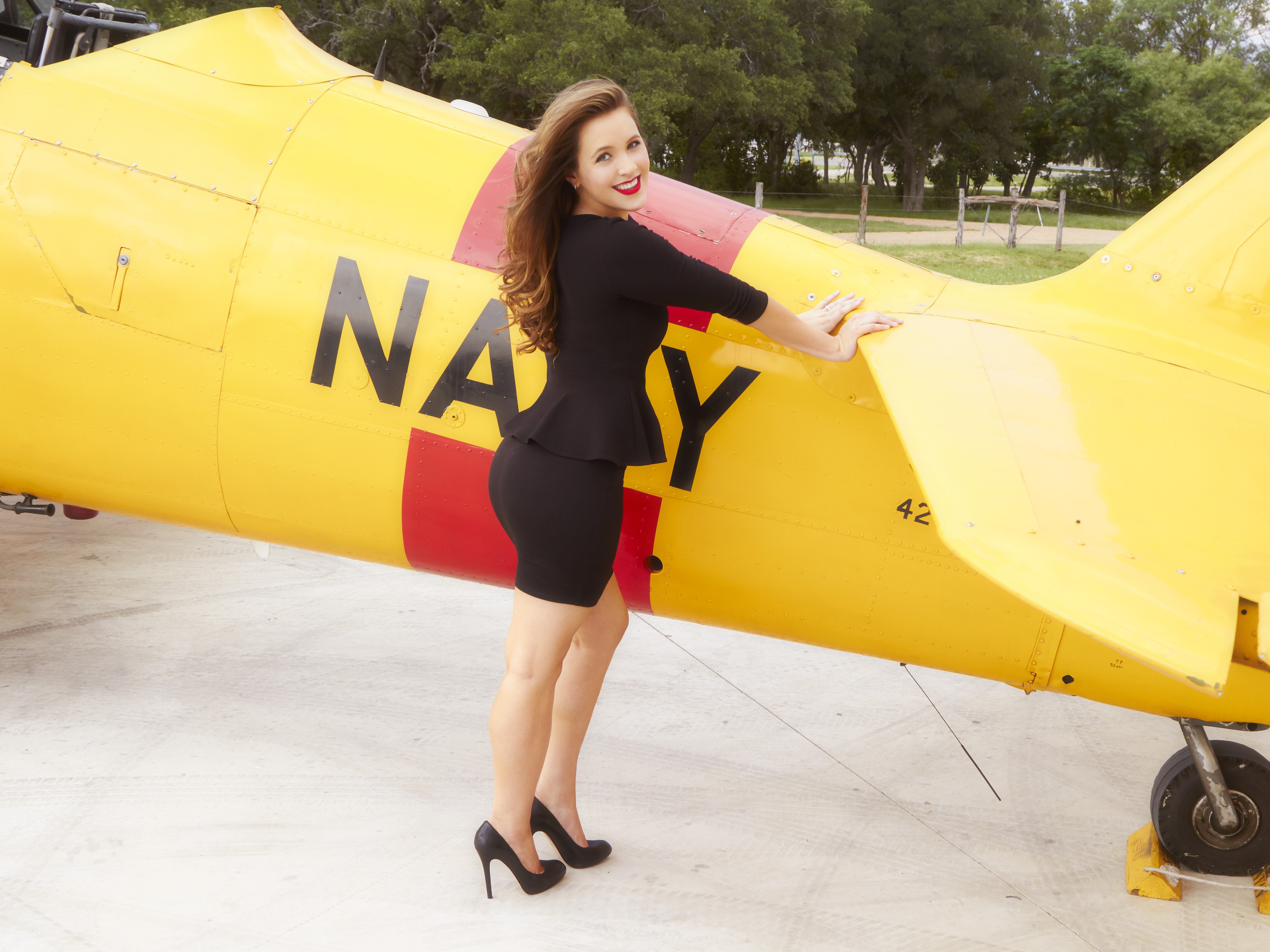 Woman posing next to a yellow Navy airplane HD Wallpaper