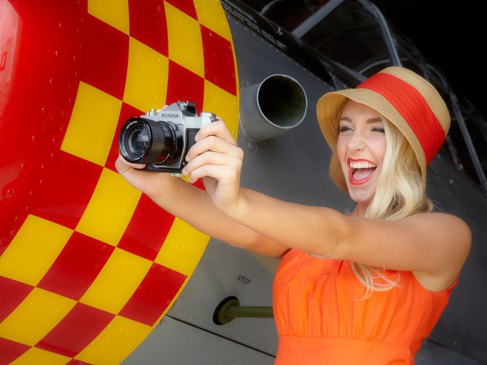 Woman in orange dress taking a selfie with a vintage camera HD Wallpaper