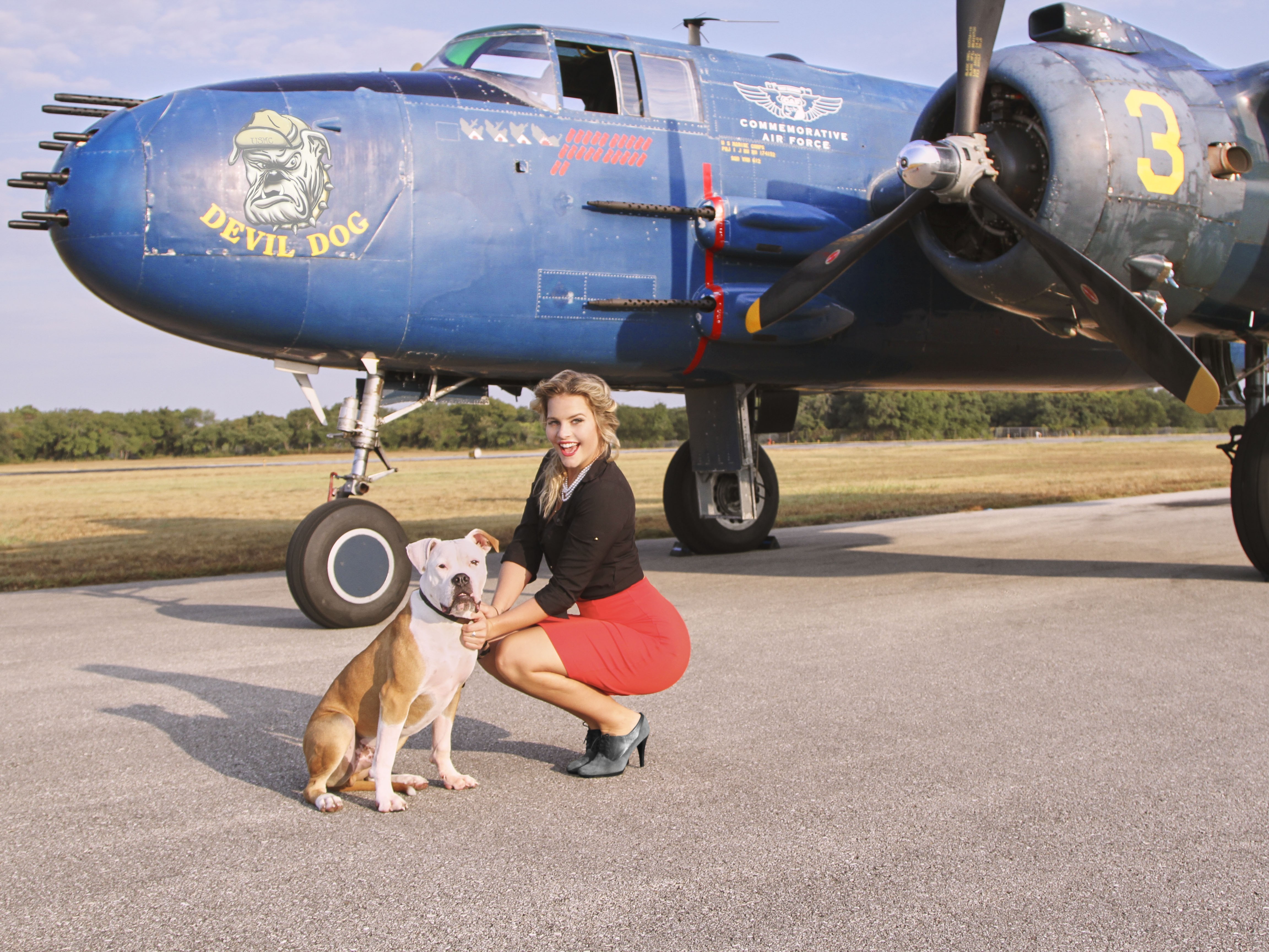 Woman and dog posing with a Commemorative Air Force "Devil Dog" airplane HD Wallpaper
