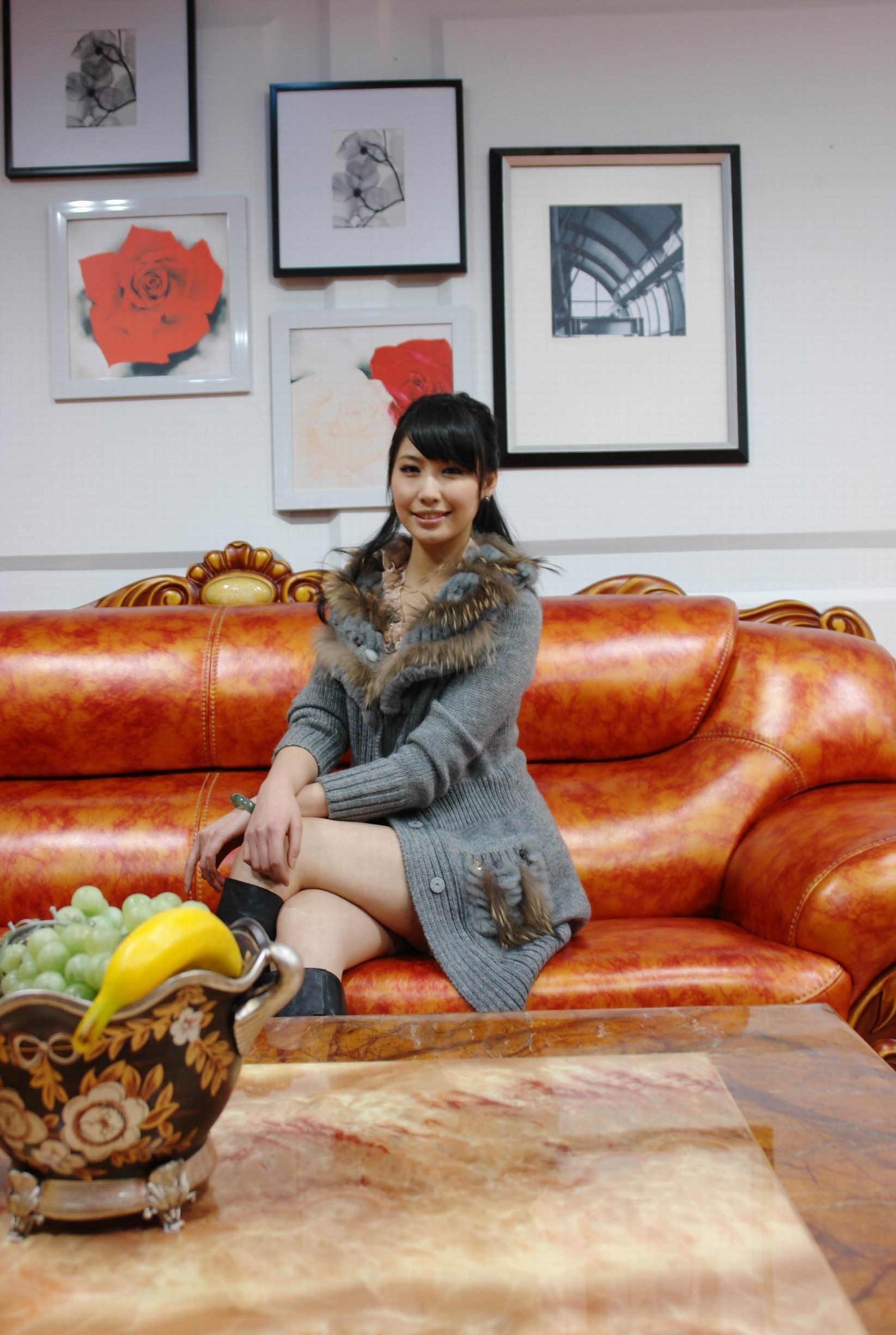 Woman sitting on a leather couch with paintings on the wall HD Wallpaper