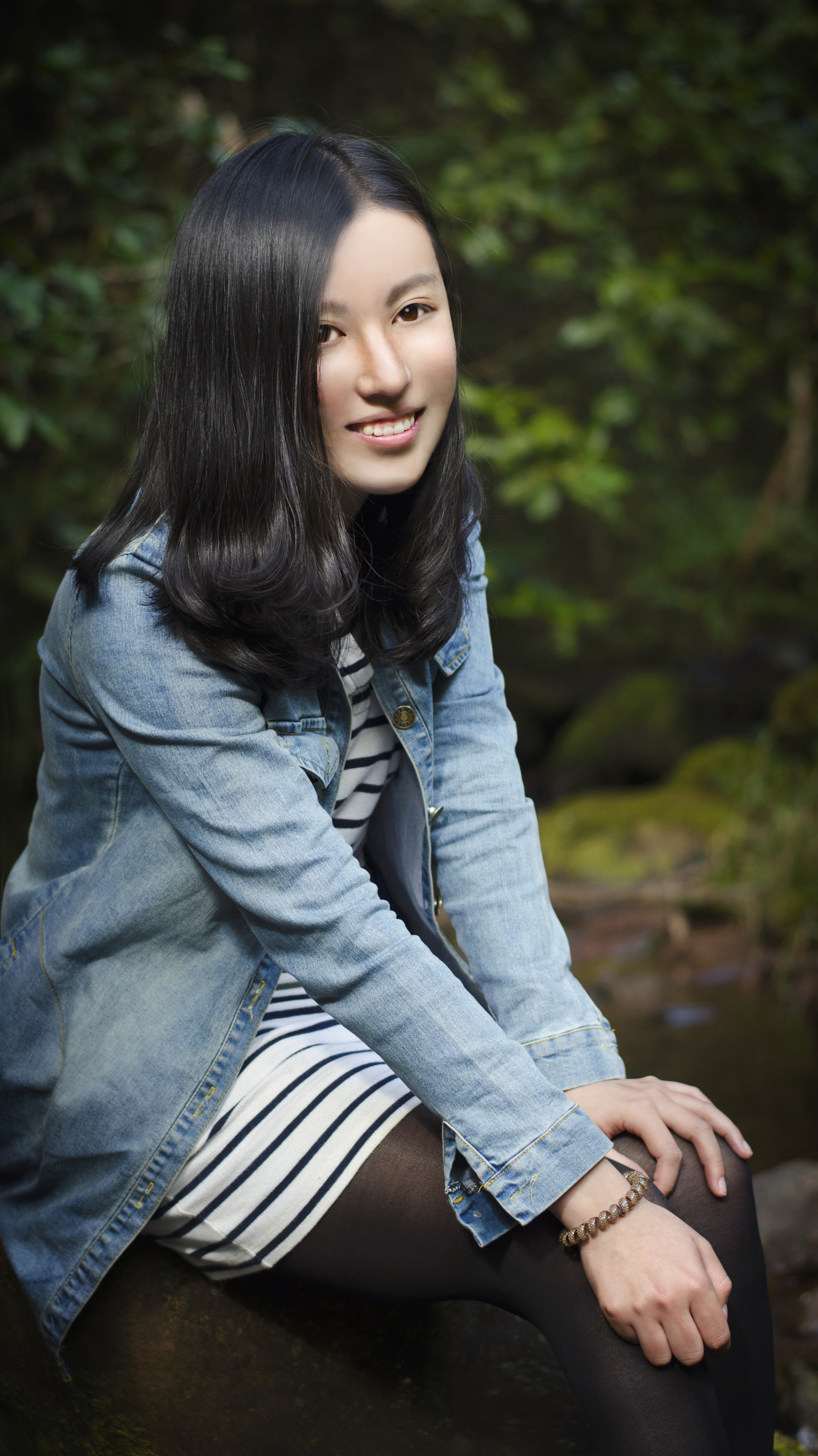 Smiling Woman in Denim Jacket Sitting Outdoors HD Wallpaper