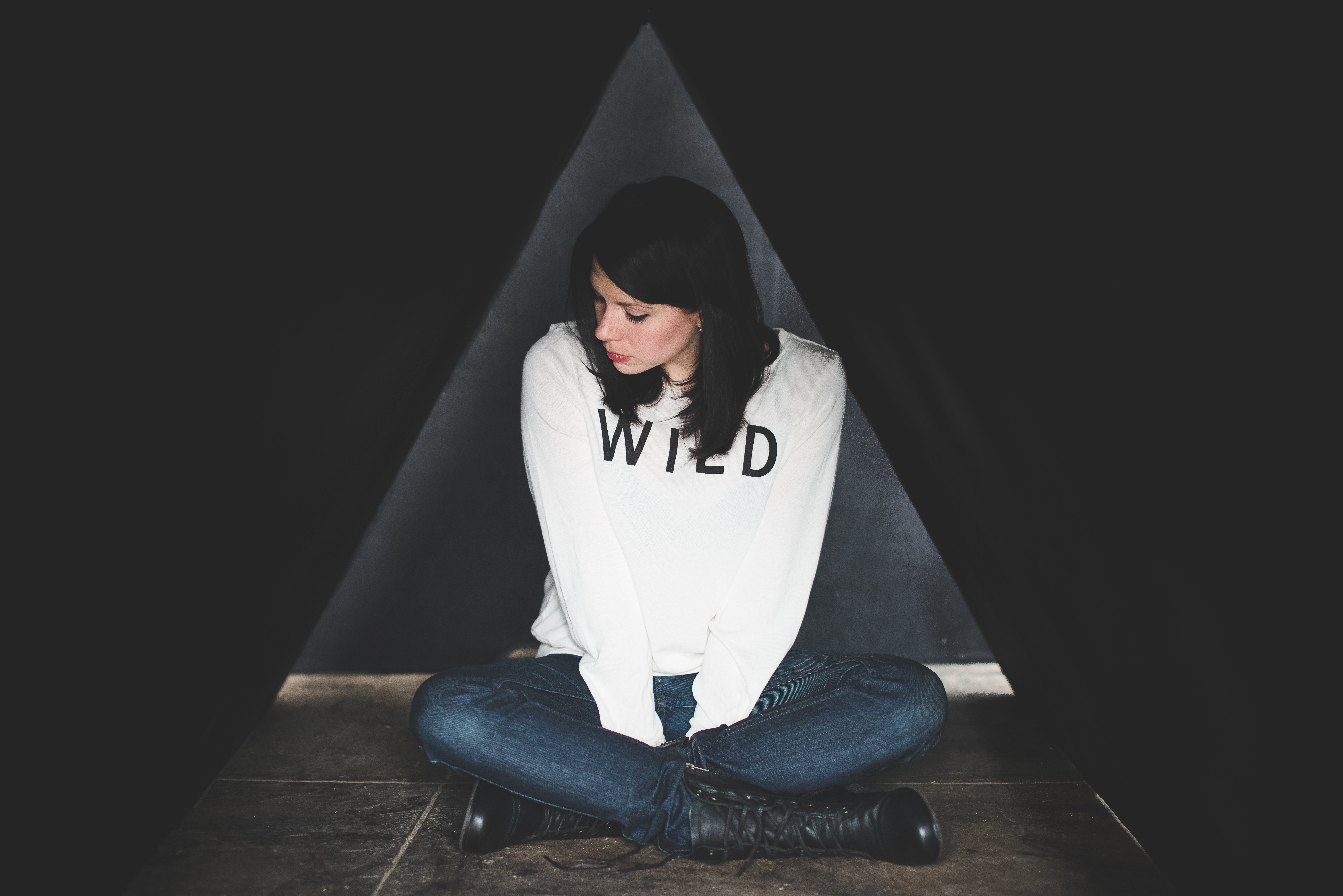 K. Flay sitting in a dark triangular space HD Wallpaper