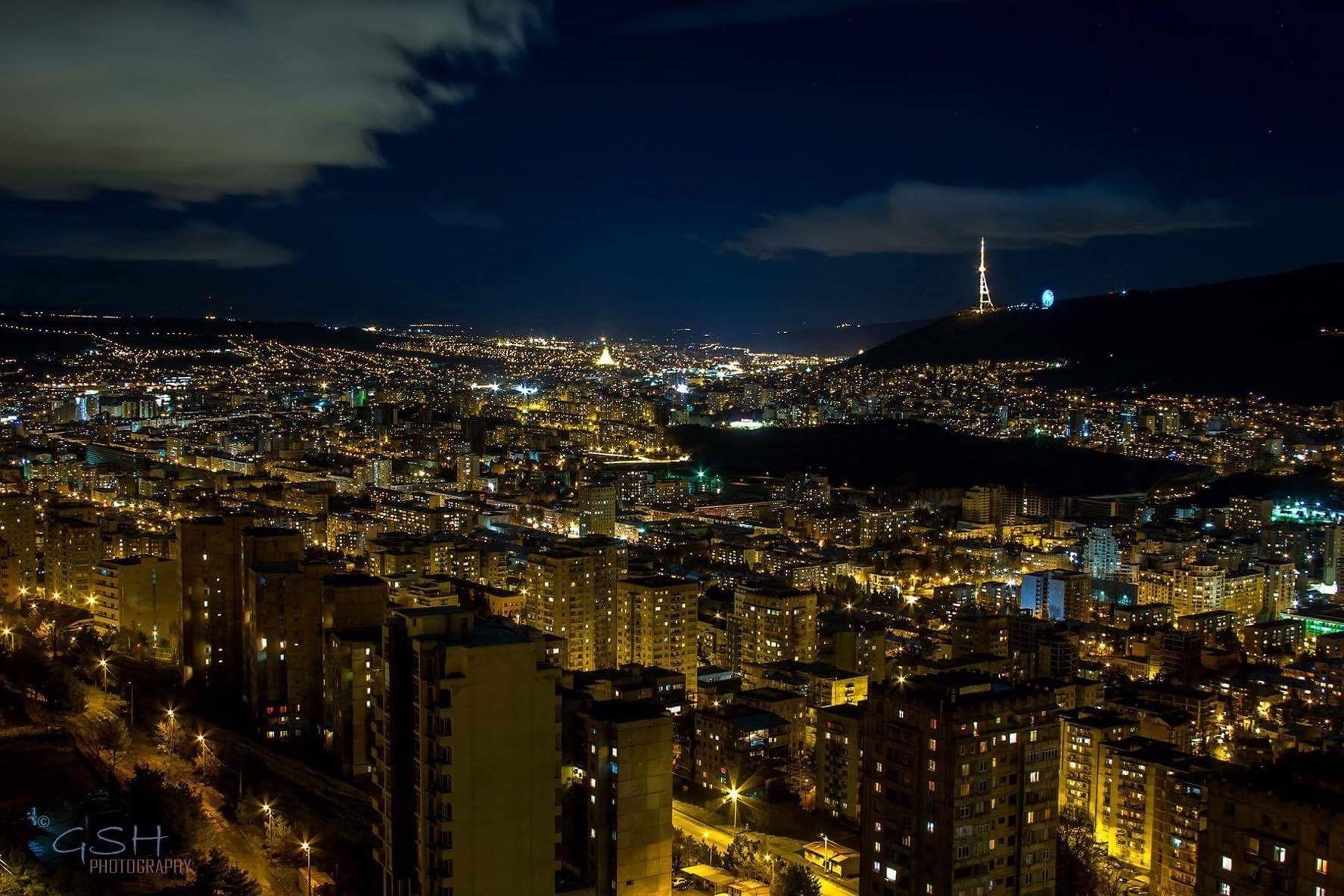 Night cityscape of Tbilisi, Georgia with illuminated buildings and a TV tower HD Wallpaper