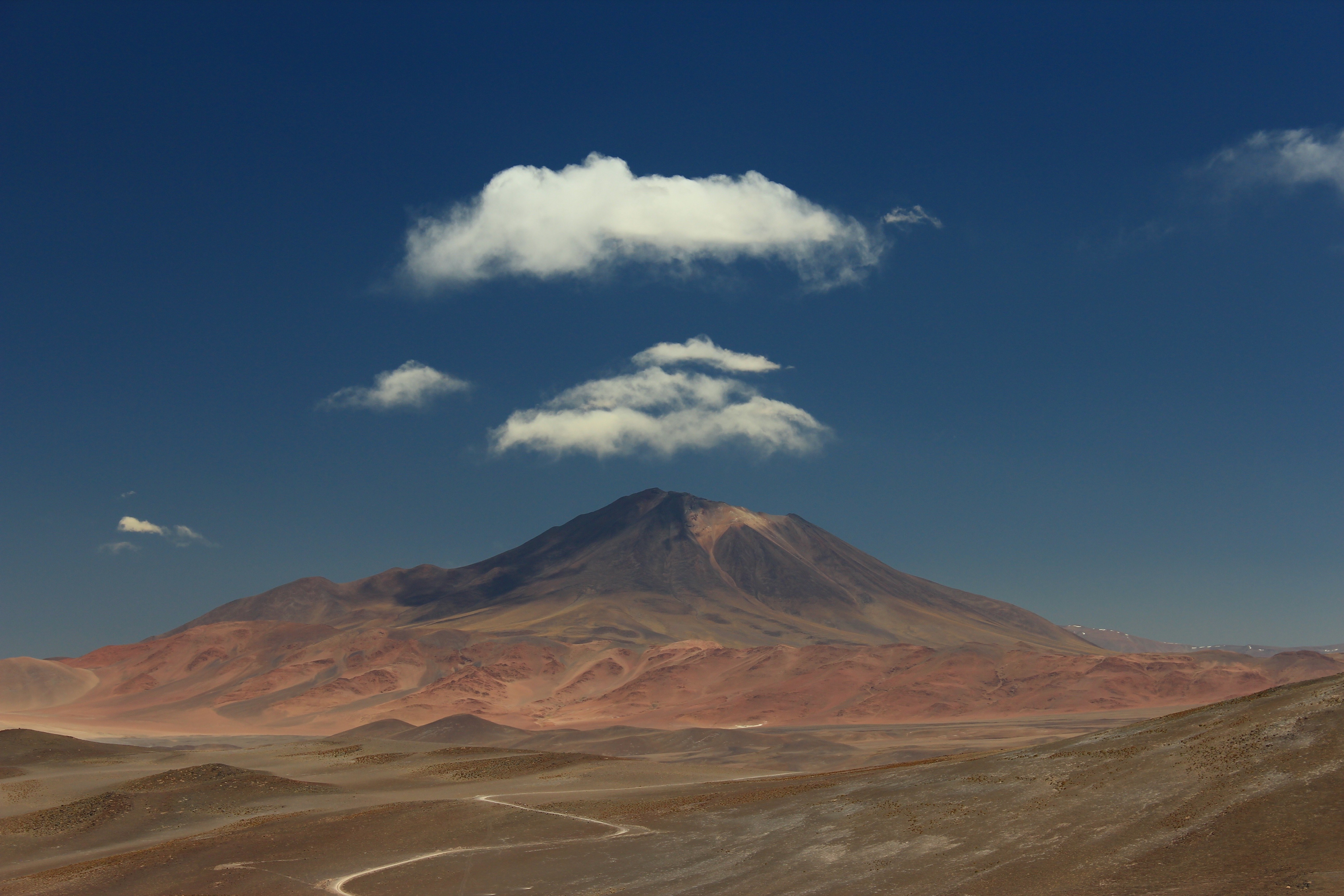 Volcano and clouds over a desert landscape HD Wallpaper