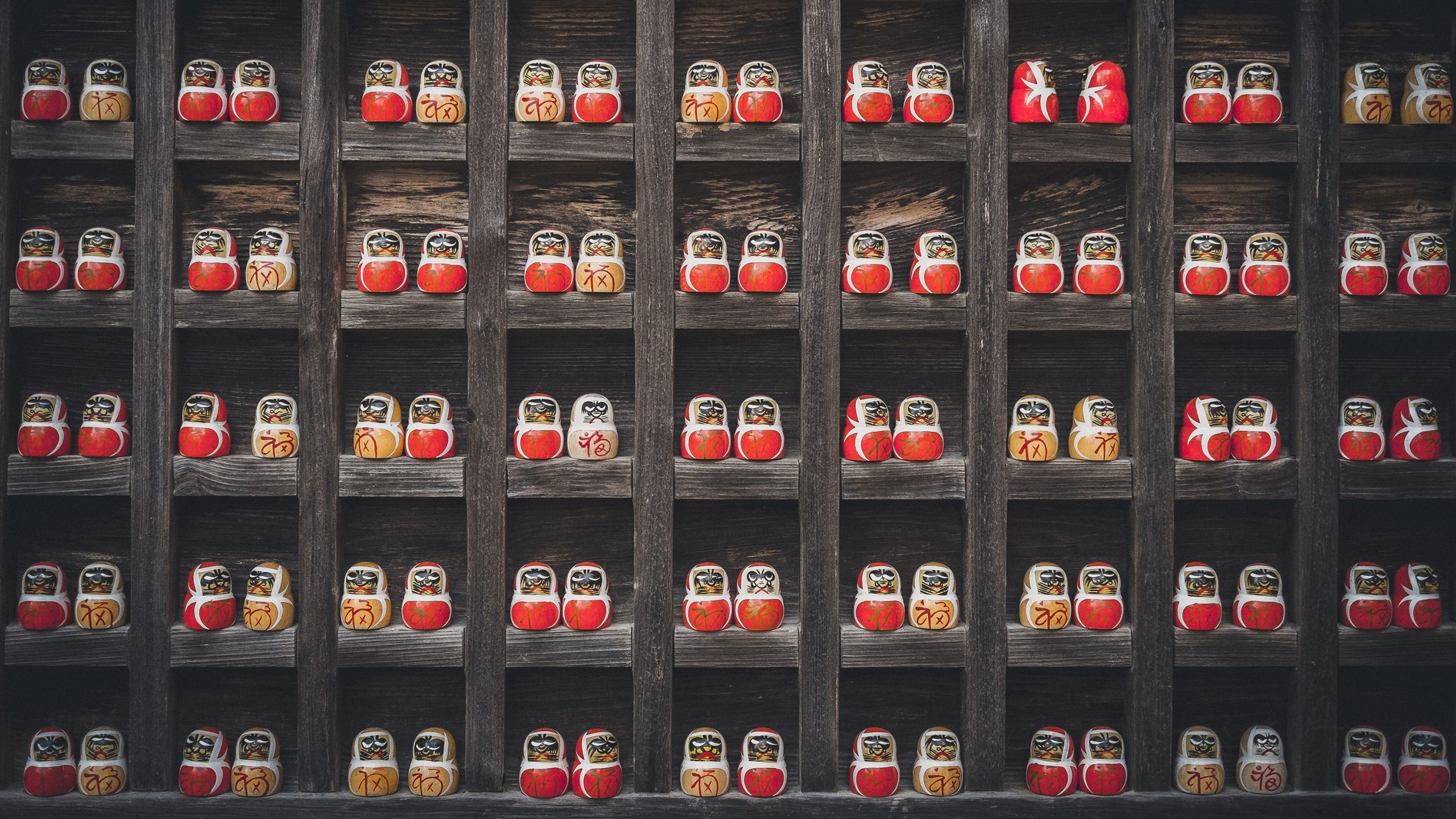 Daruma dolls displayed on wooden shelves HD Wallpaper