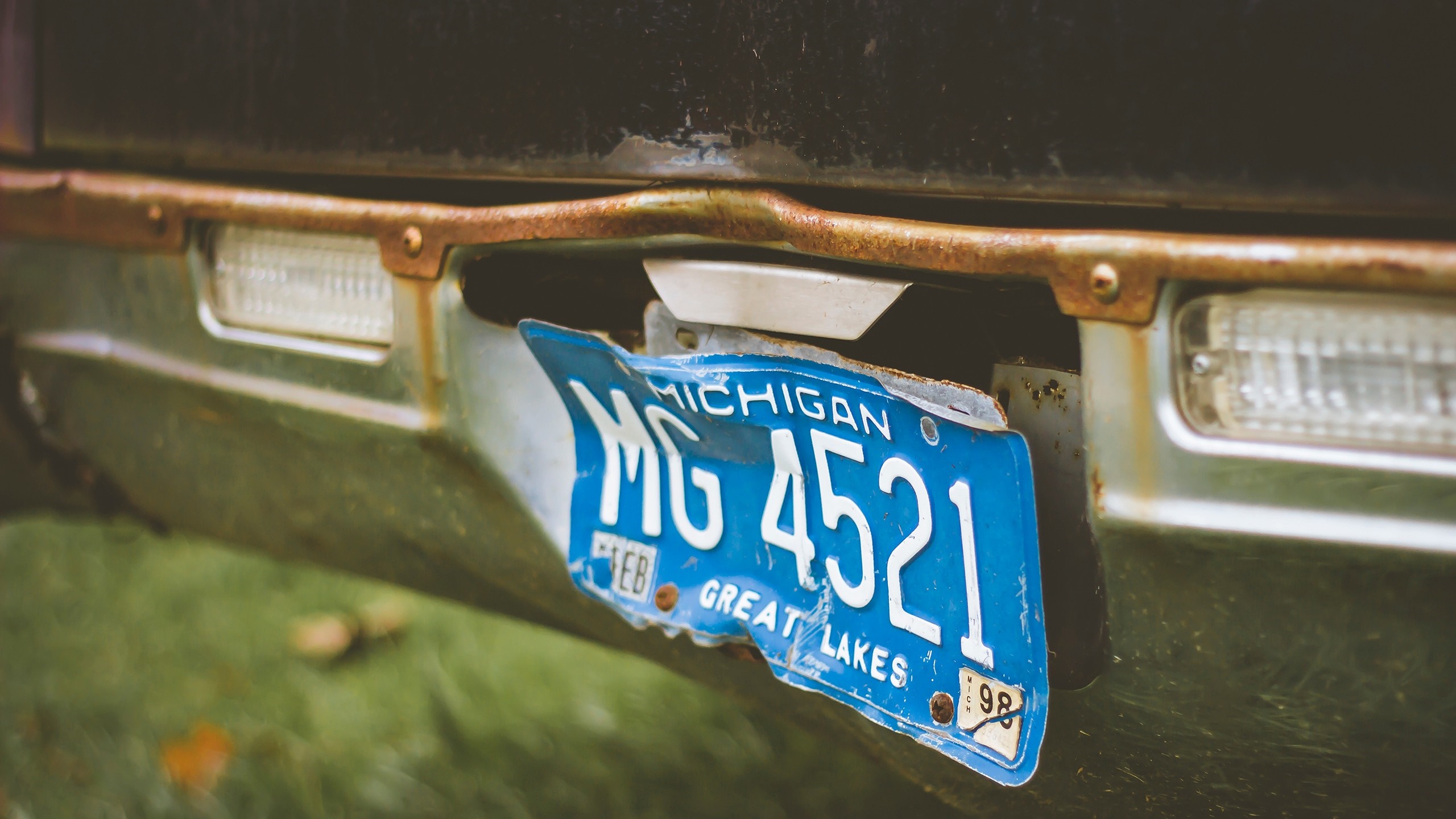 Bent Michigan license plate MG 4521 on a rusty bumper HD Wallpaper