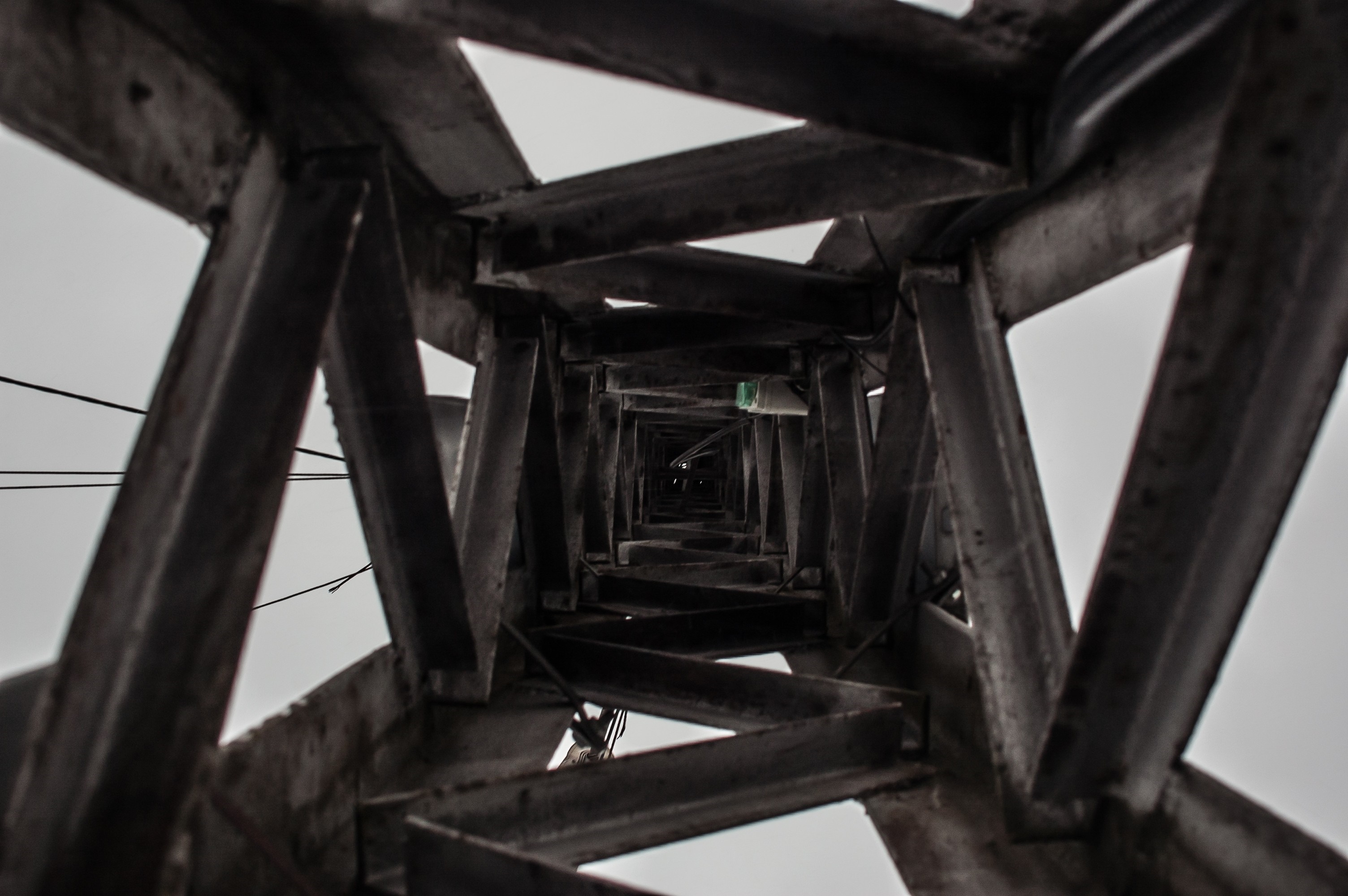 Looking up through a metal tower structure HD Wallpaper