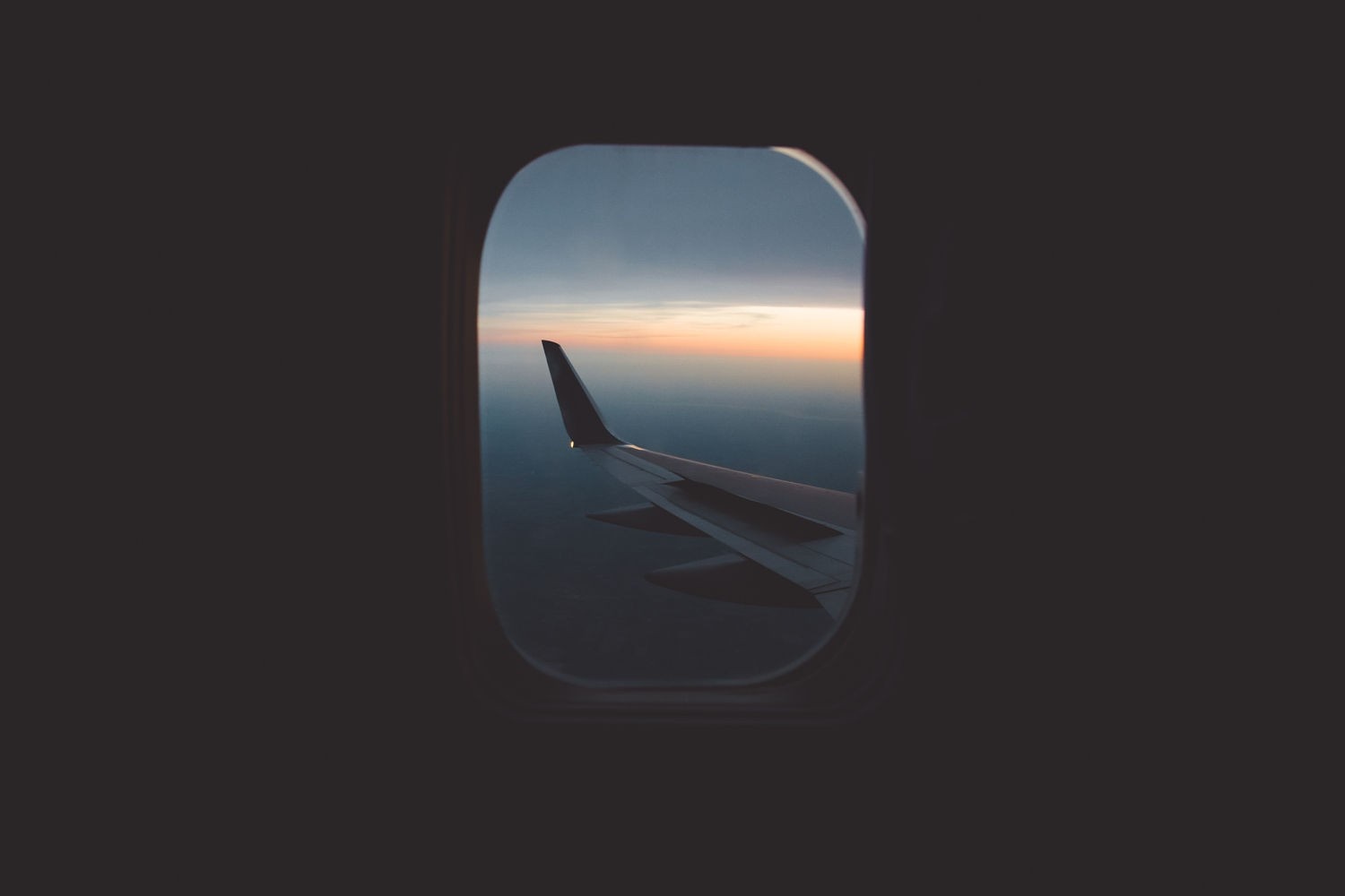 Airplane wing seen through a window at sunset HD Wallpaper