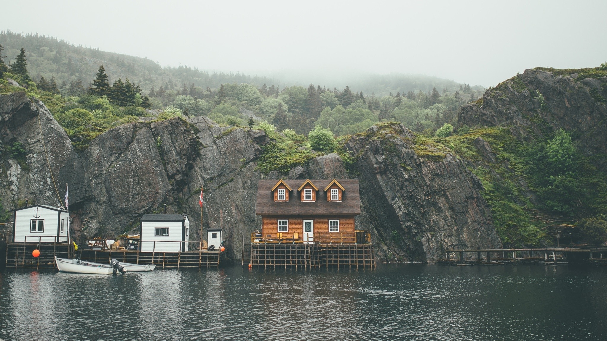 Wooden houses on stilts by a rocky cove with fog. HD Wallpaper