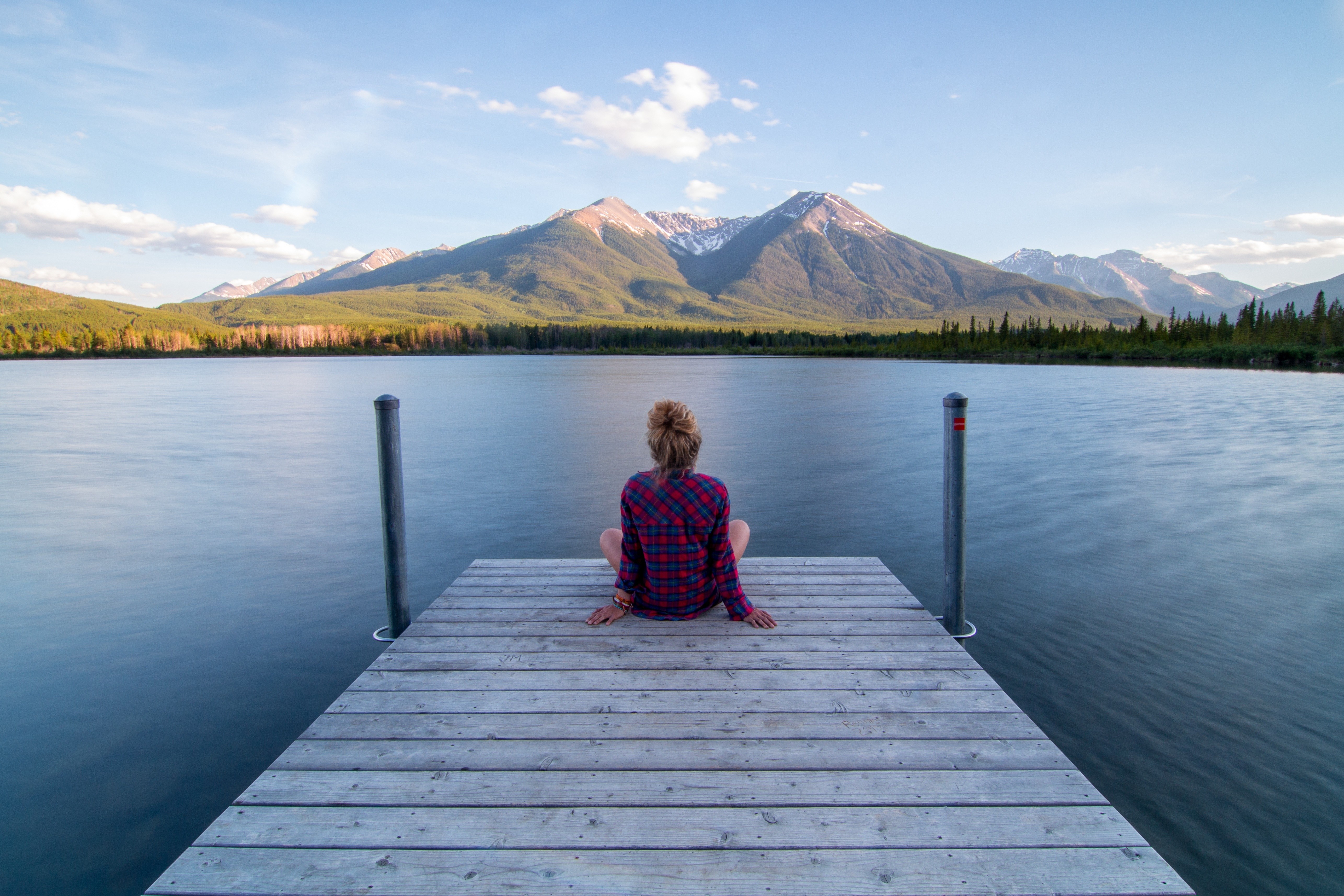 Woman sitting on a dock overlooking a lake and mountains HD Wallpaper