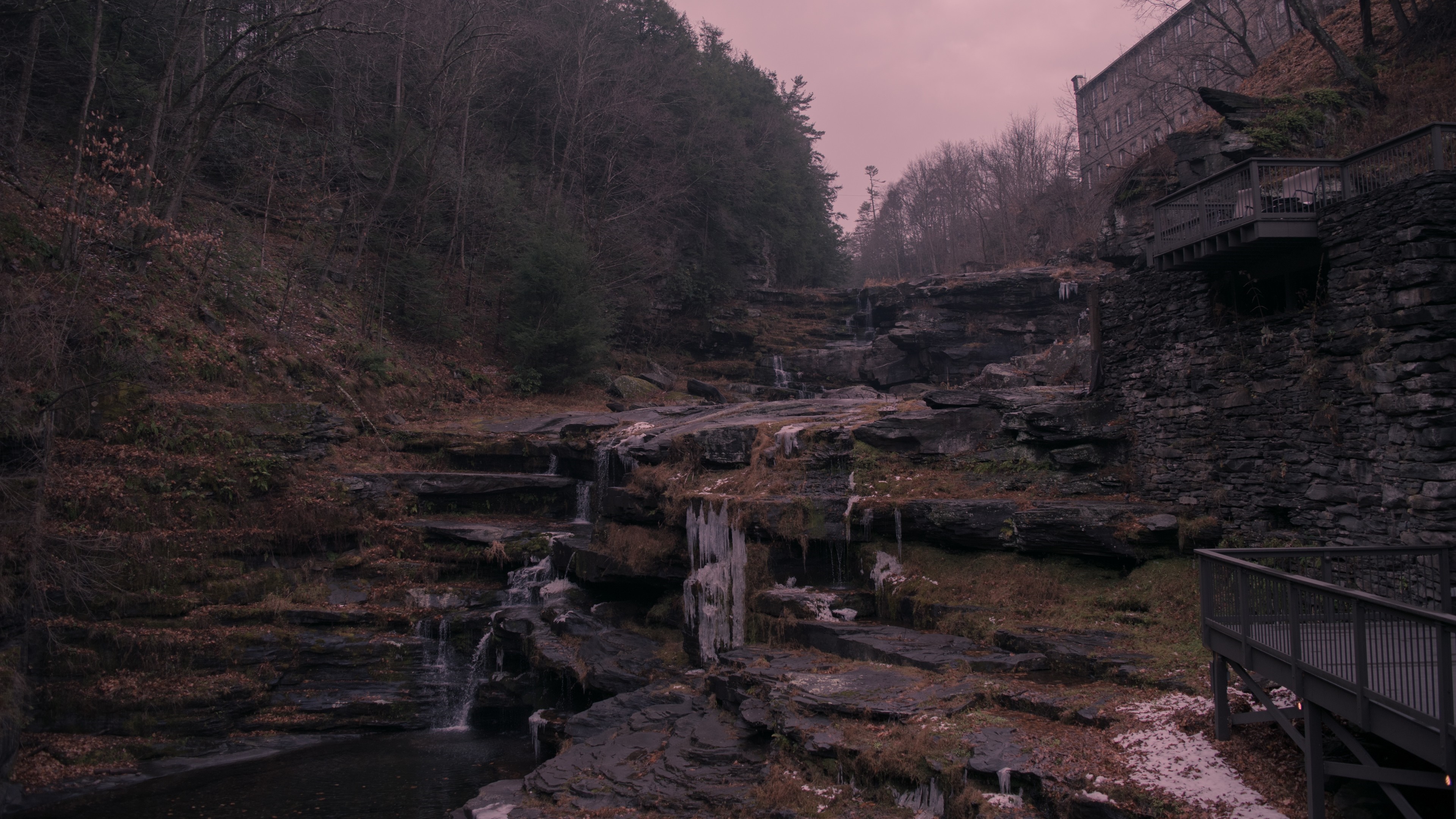 Waterfall cascading over rocks with wooden walkways HD Wallpaper