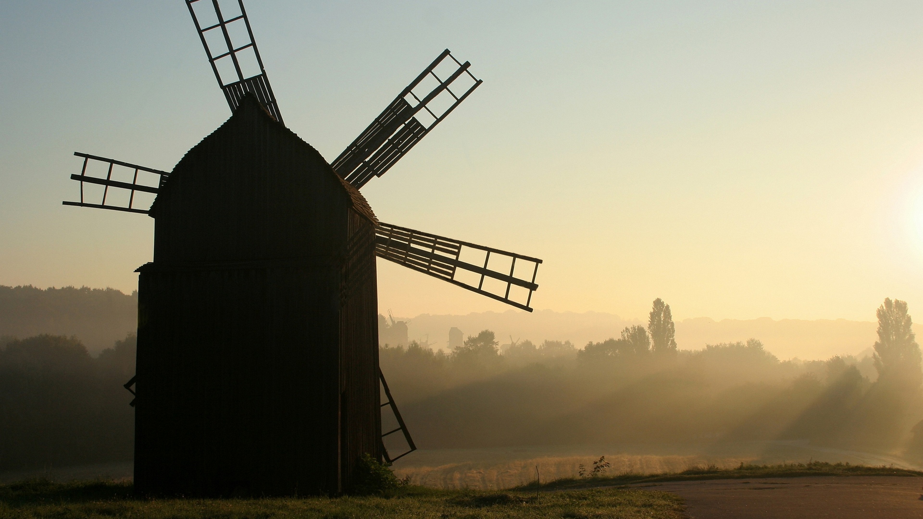 Silhouette of a windmill at sunrise with mist HD Wallpaper