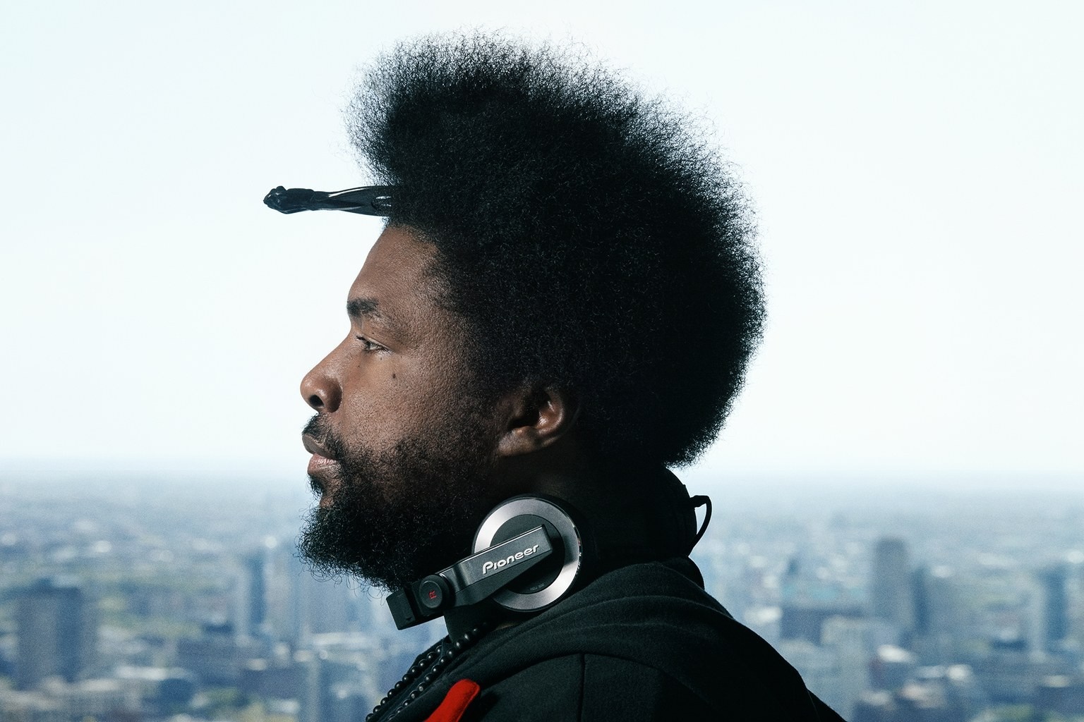 Questlove with Pioneer headphones overlooking city HD Wallpaper