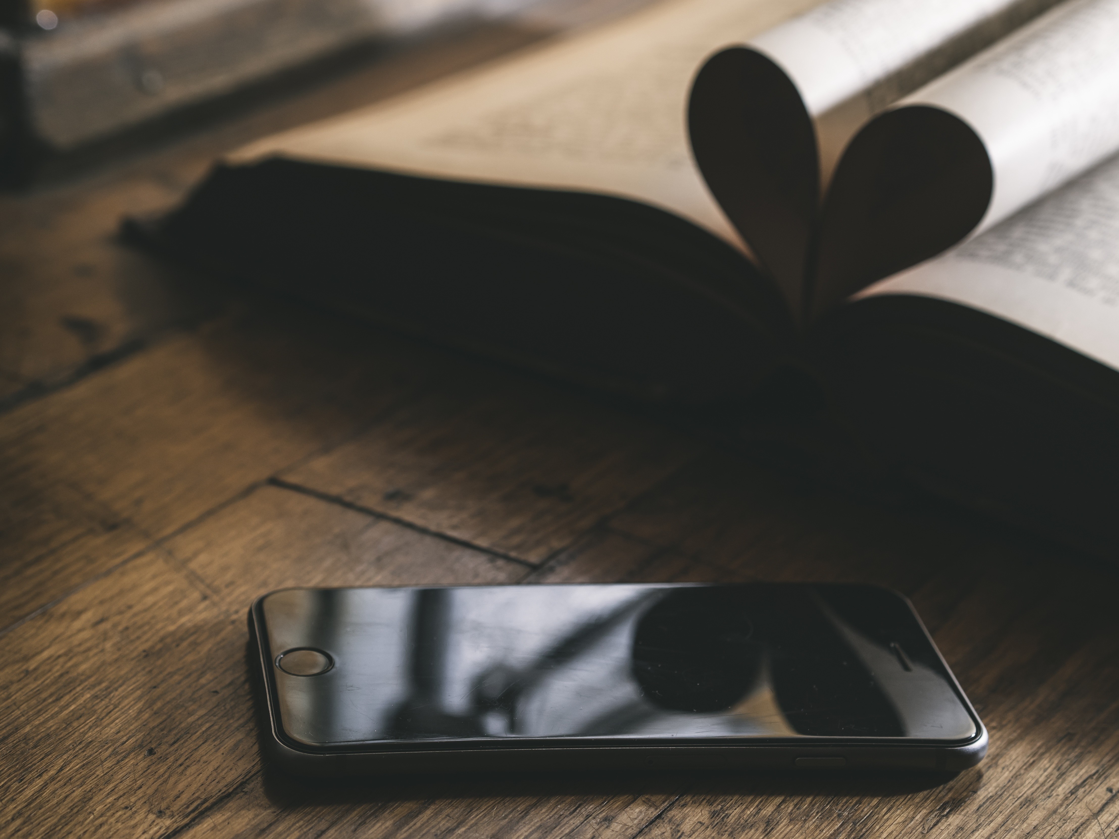 iPhone and book with heart-shaped pages on wood HD Wallpaper