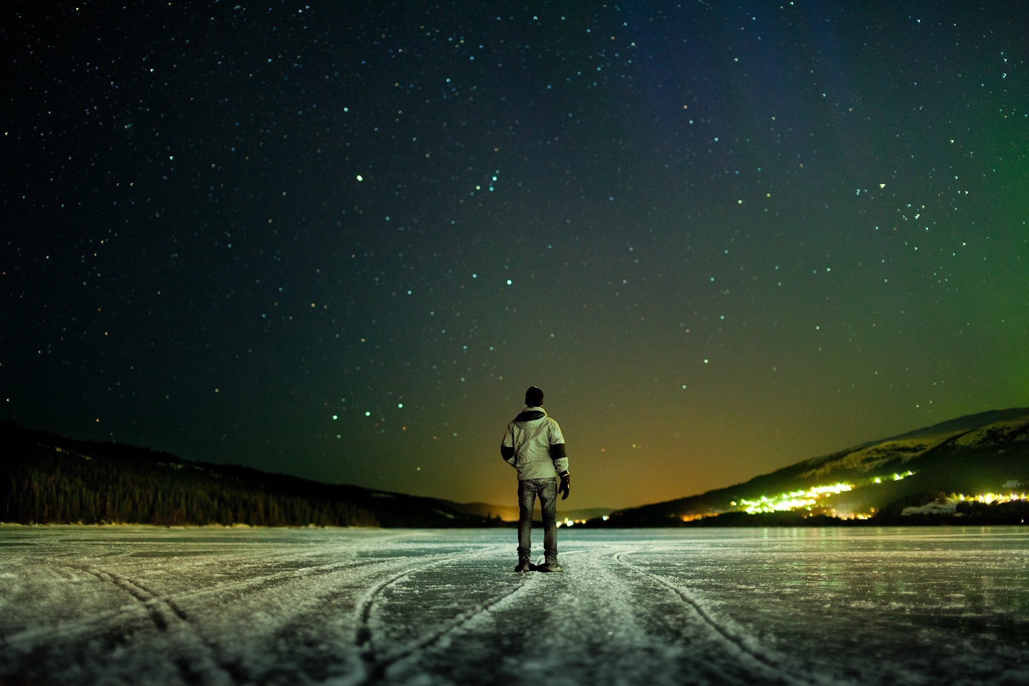 Man standing on frozen lake under starry night sky in Norway HD Wallpaper