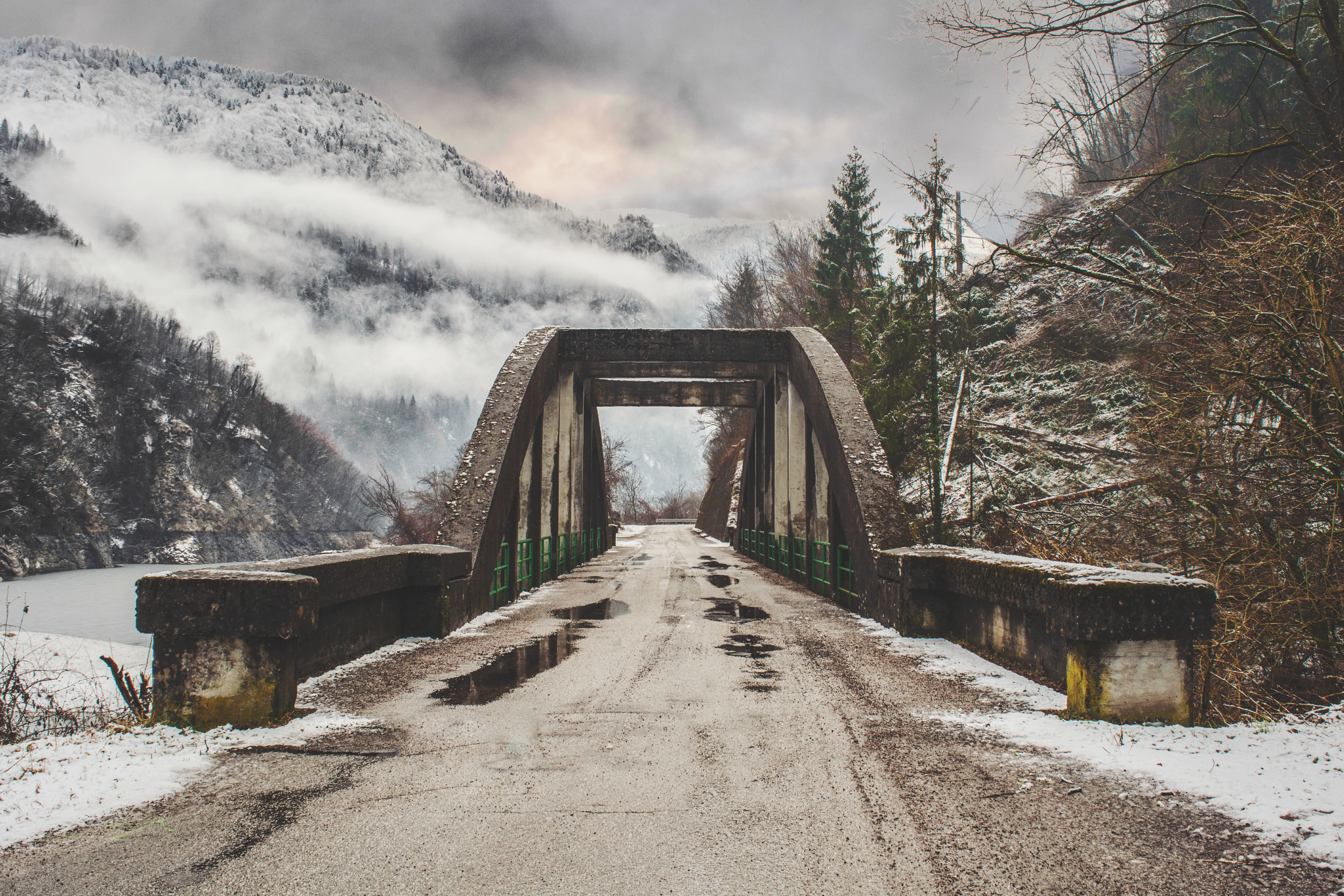 Concrete arch bridge over a snowy mountain road HD Wallpaper