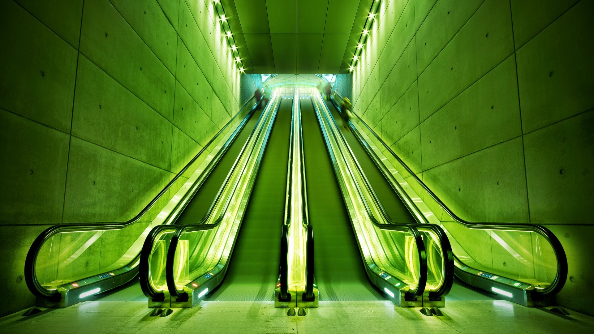 Green escalators in a concrete tunnel with lights HD Wallpaper