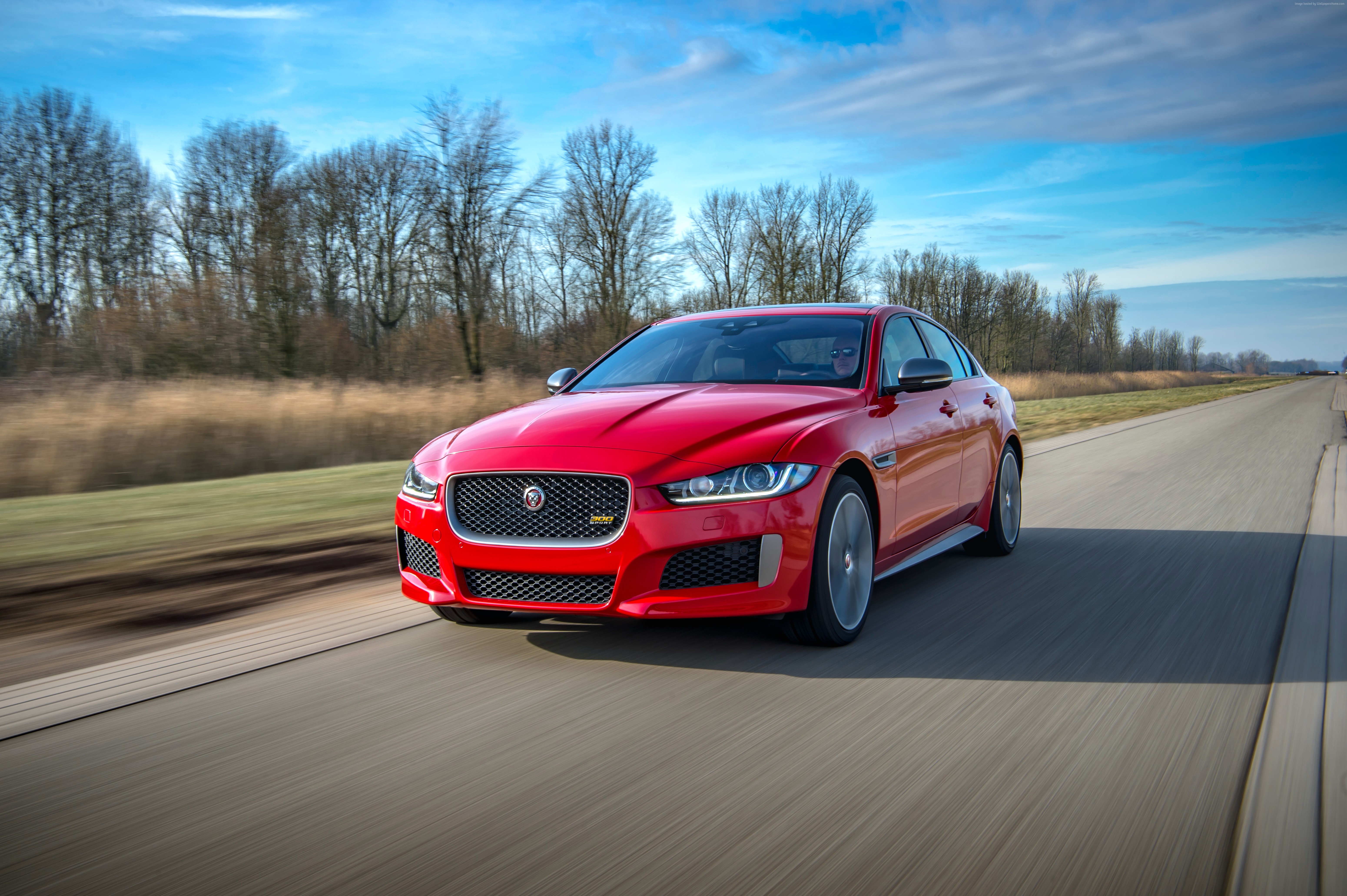 Red Jaguar XE 300 Sport driving on a road HD Wallpaper
