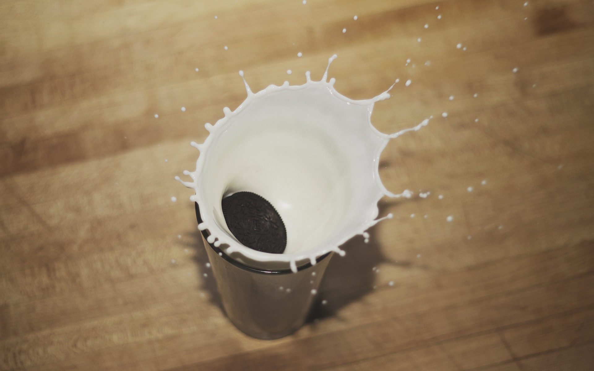 Oreo cookie splashing into milk in a glass HD Wallpaper