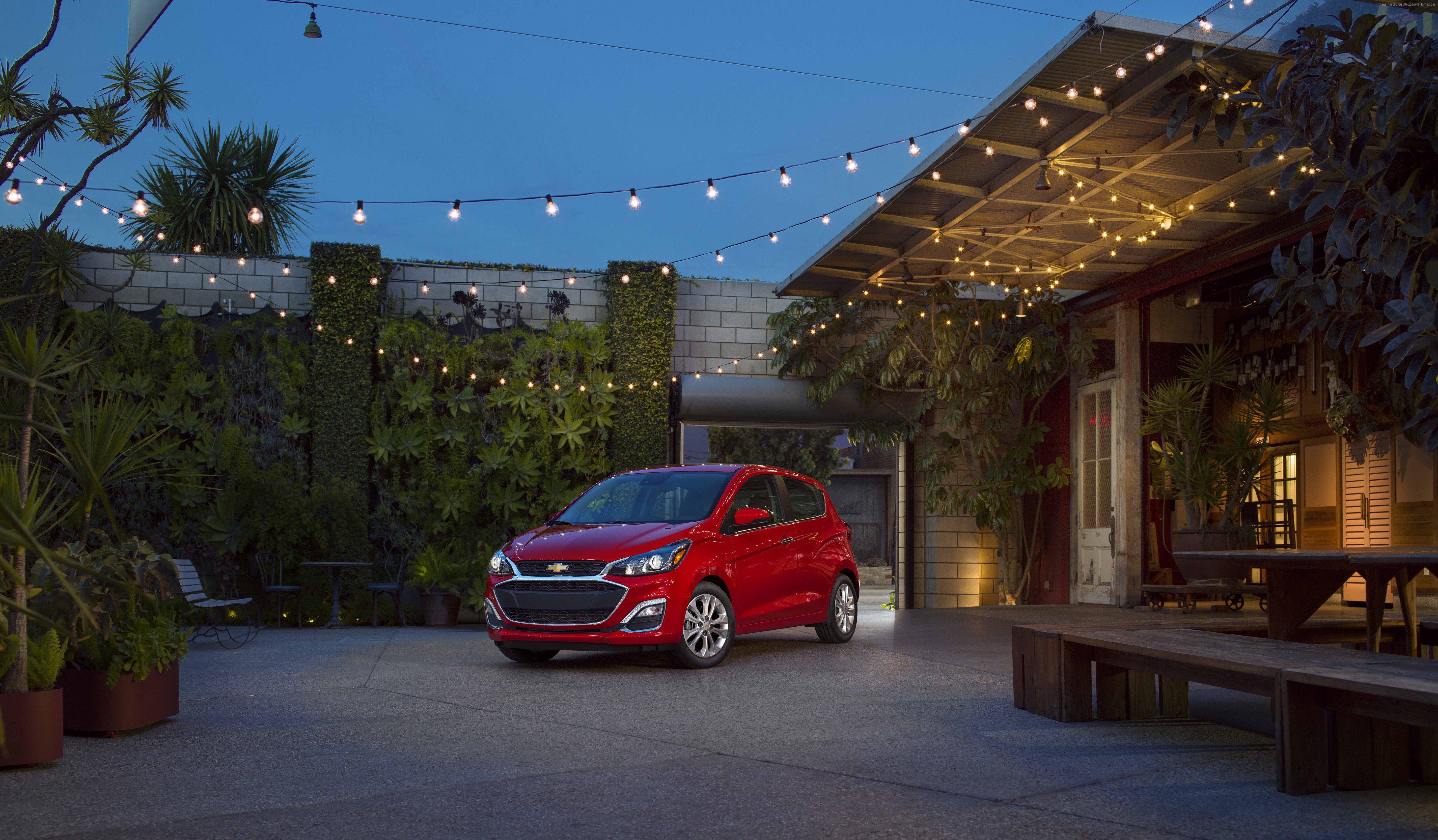 Red Chevrolet Spark parked in a courtyard at dusk HD Wallpaper