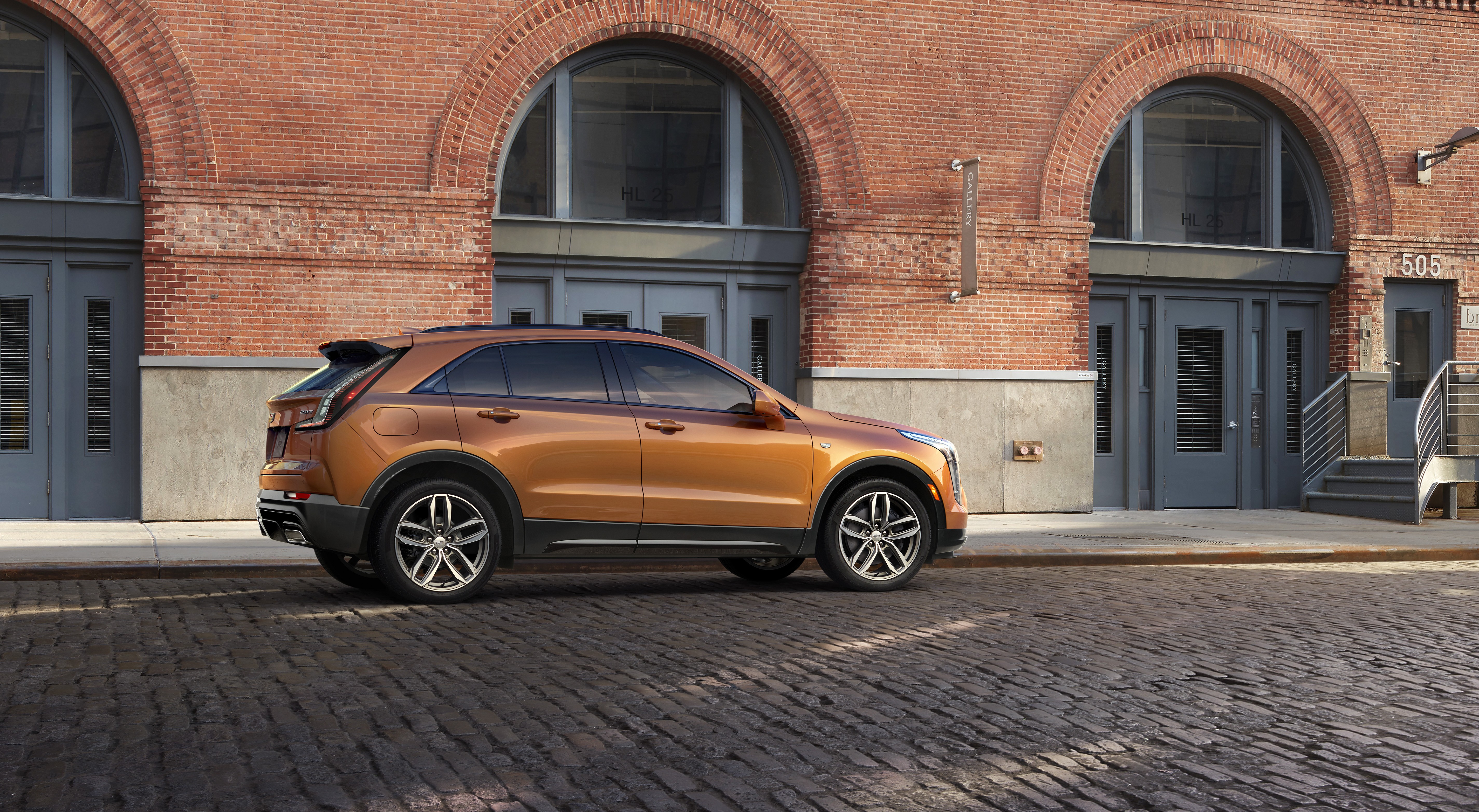 Cadillac XT4 SUV parked on cobblestone street HD Wallpaper
