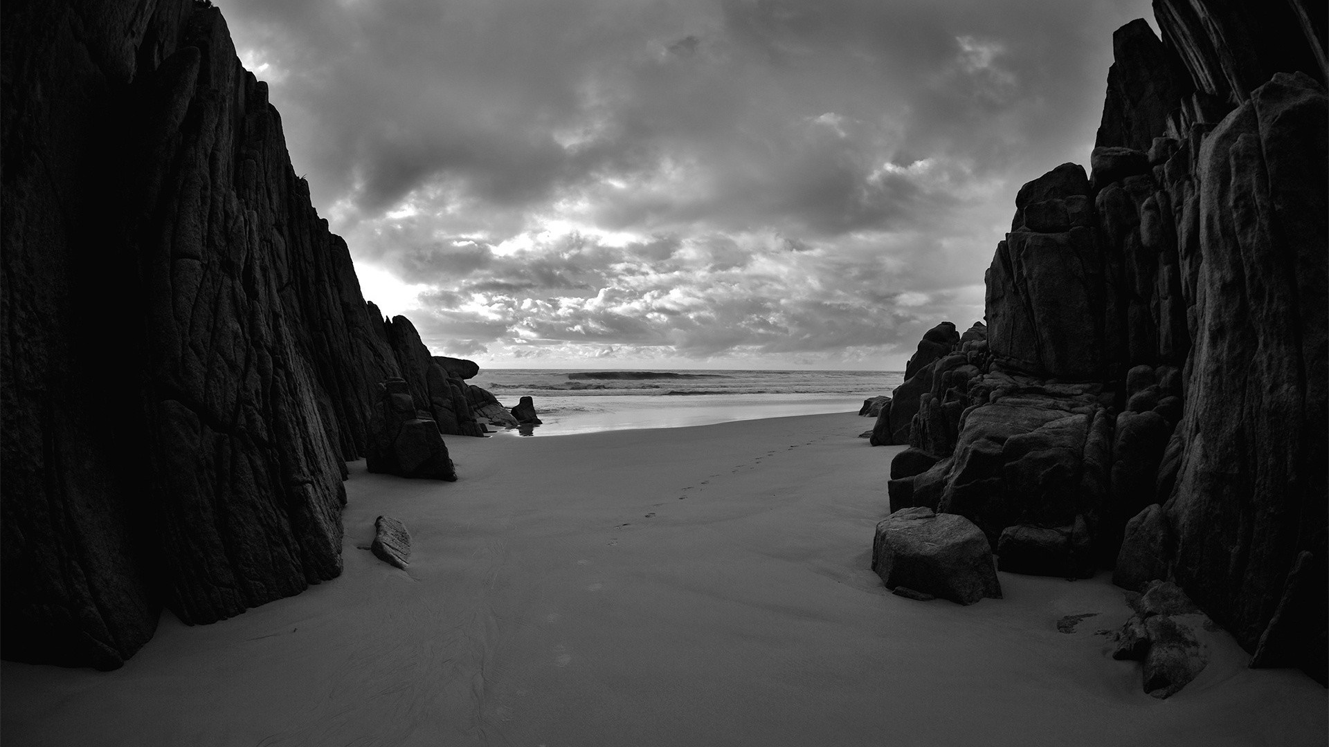 Monochrome beach with rocky cliffs and cloudy sky HD Wallpaper