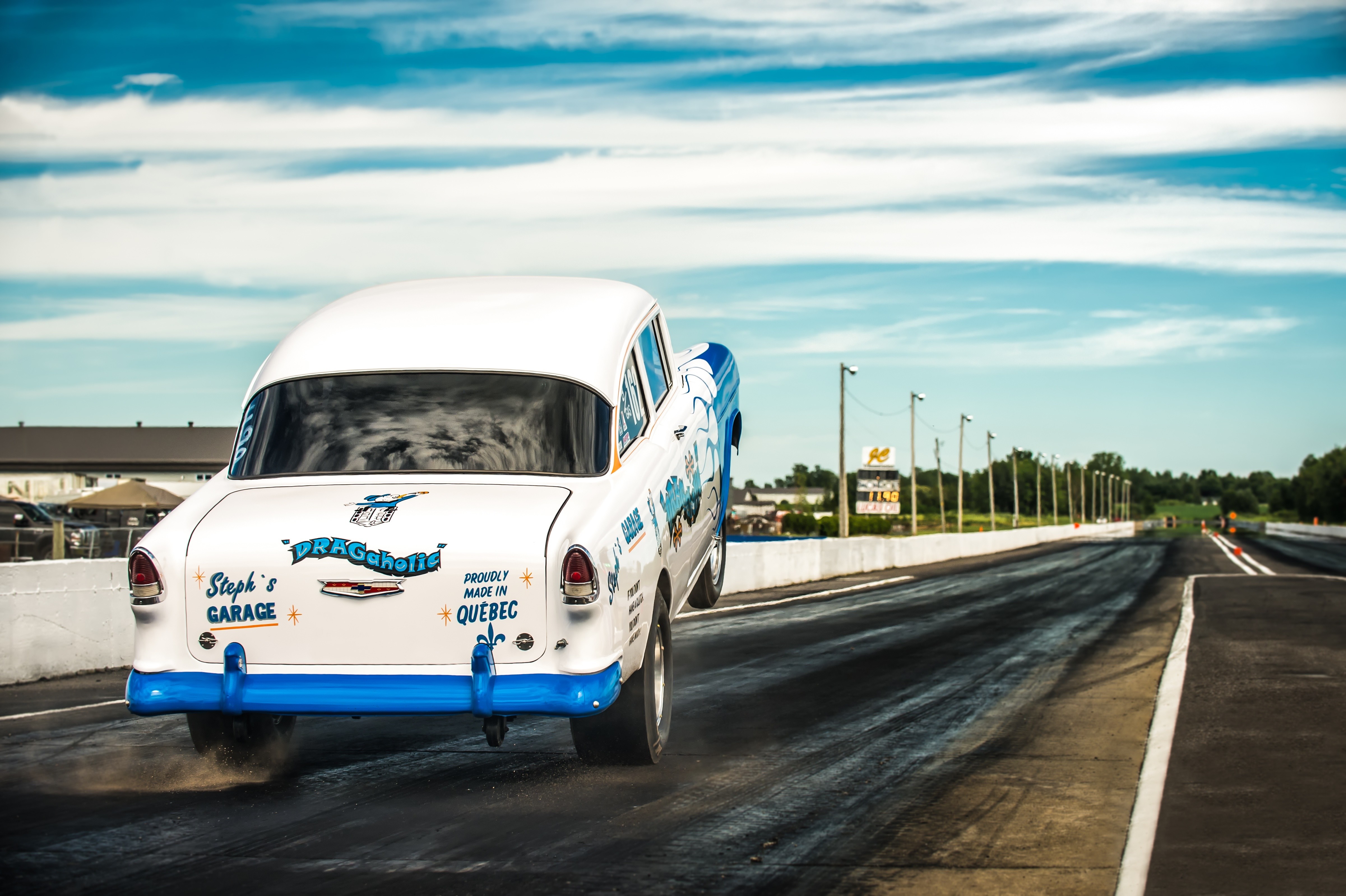 White drag racing car performing a wheelie on a track HD Wallpaper