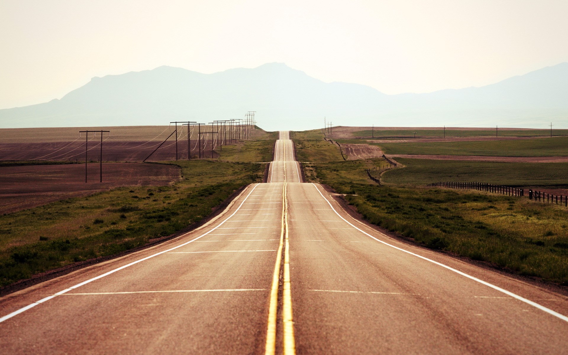 Empty highway stretching towards distant mountains HD Wallpaper
