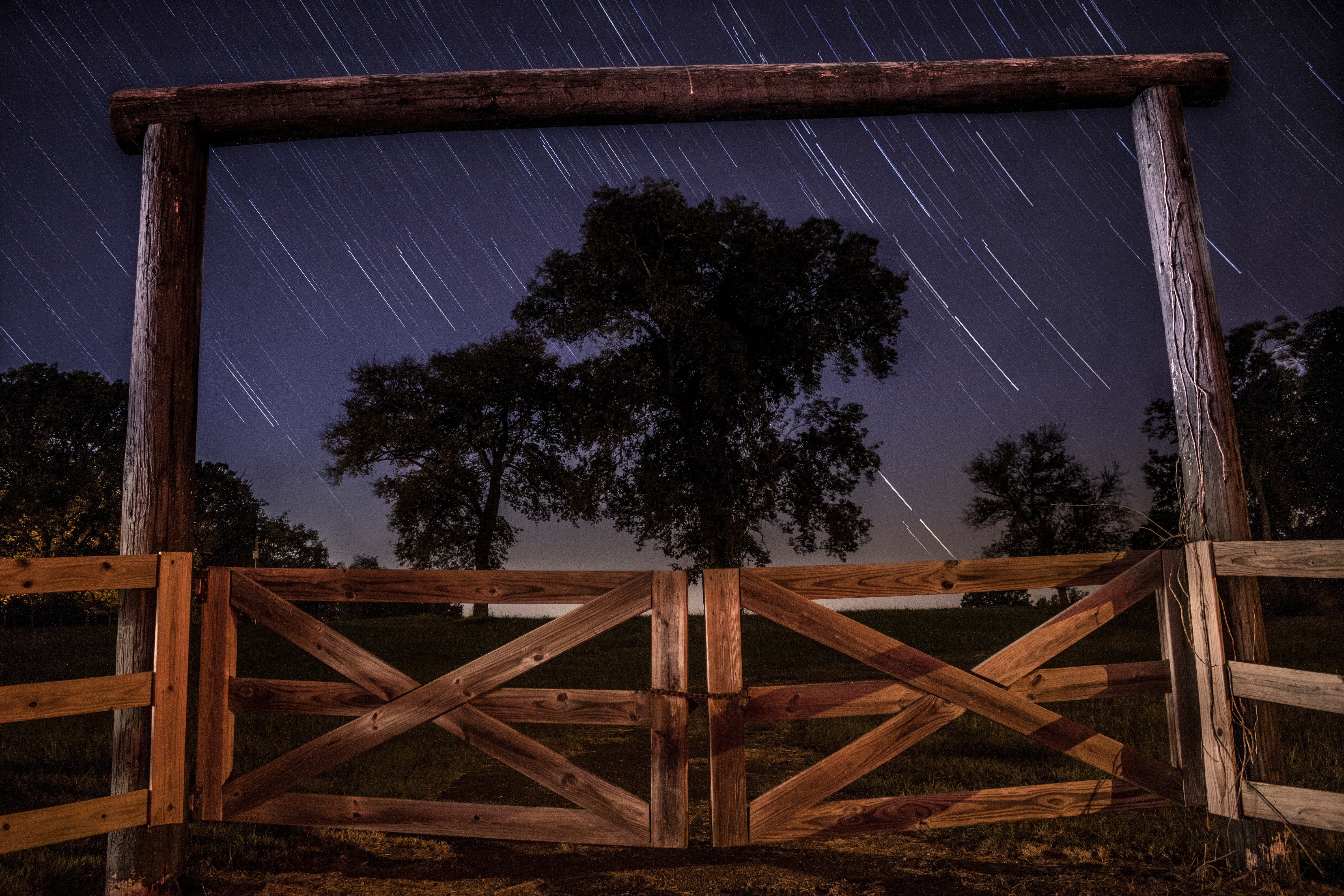 Wooden gate under star trails at night HD Wallpaper