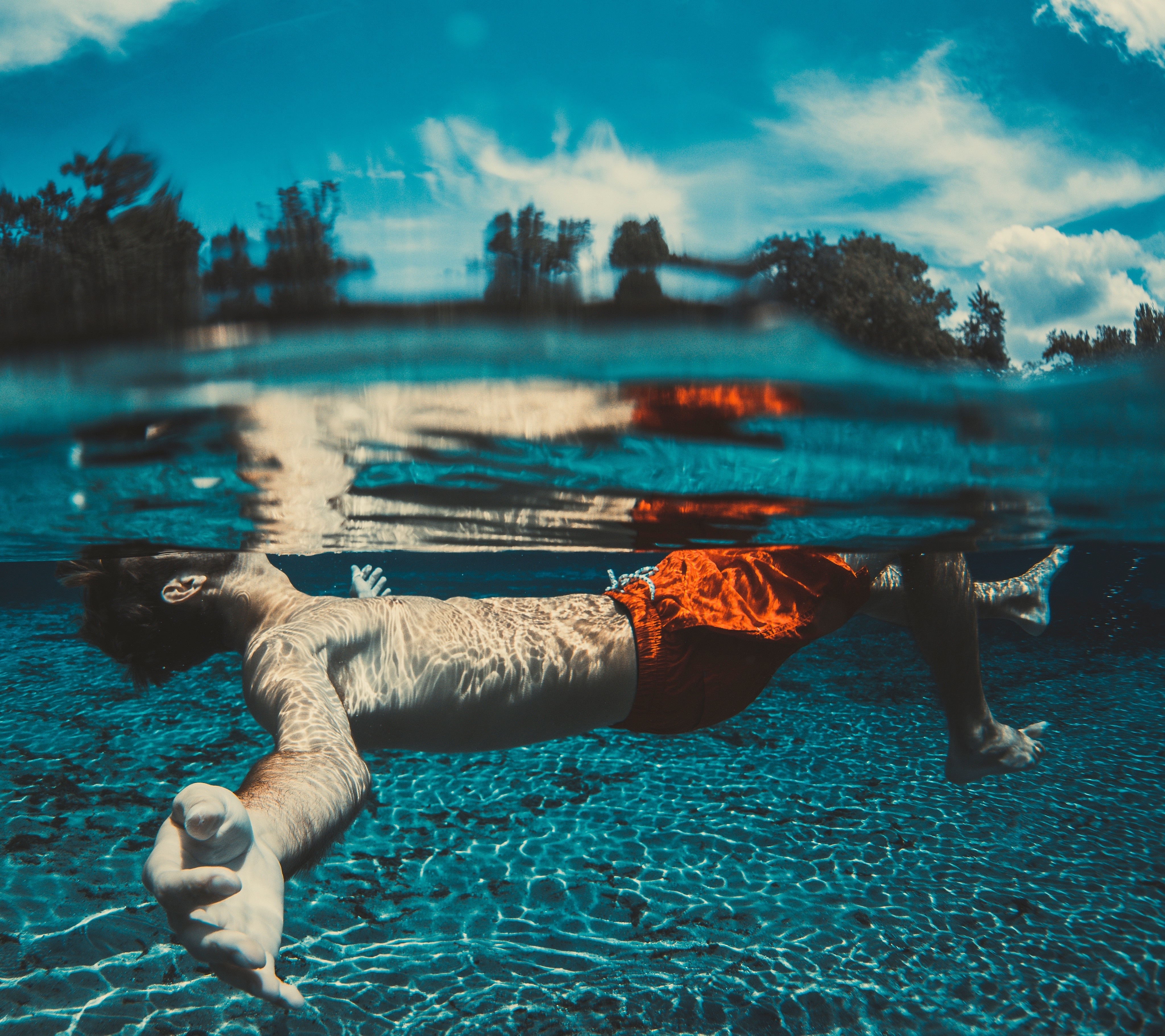 Man floating underwater in a pool HD Wallpaper