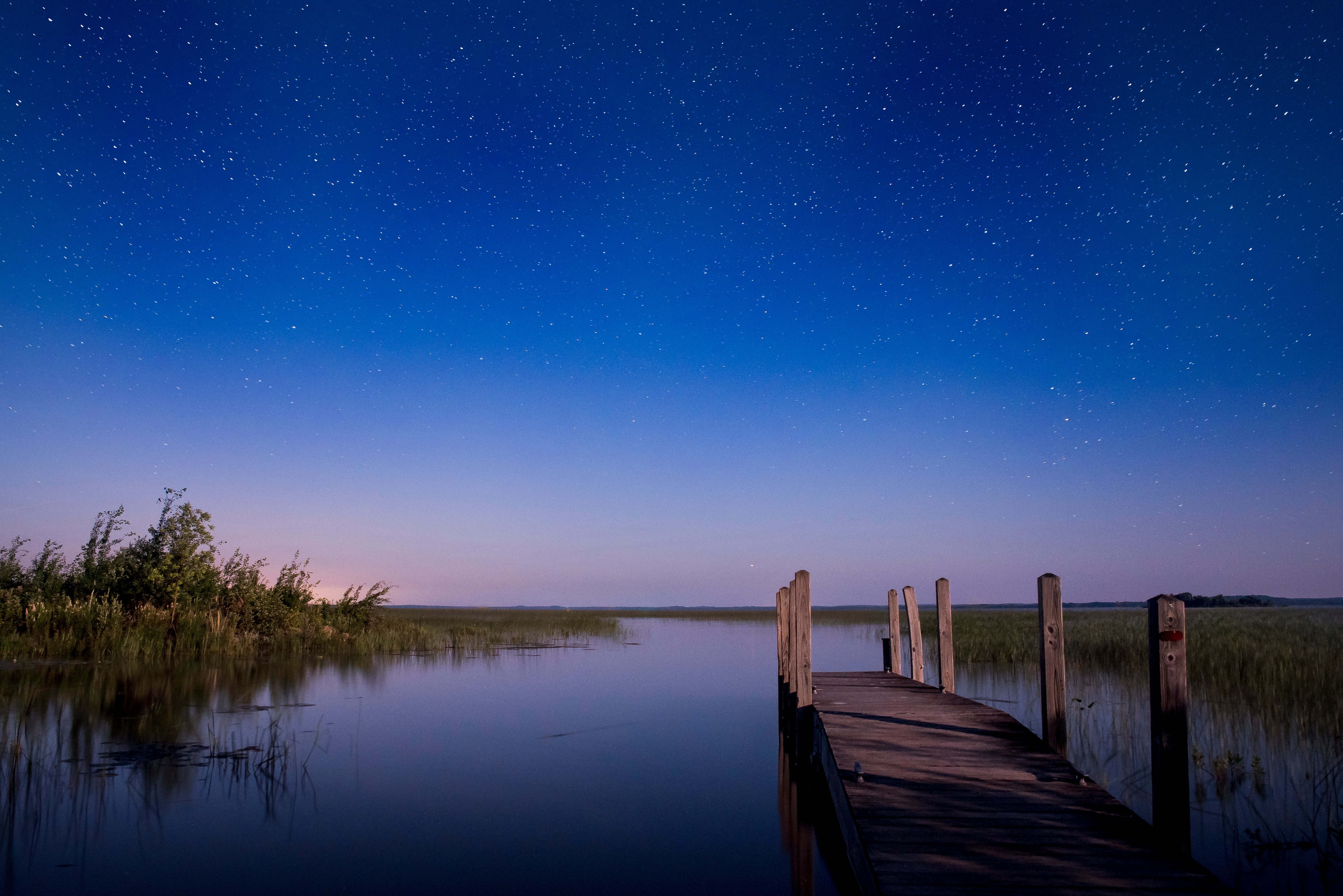 Wooden dock on a lake under a starry night sky HD Wallpaper
