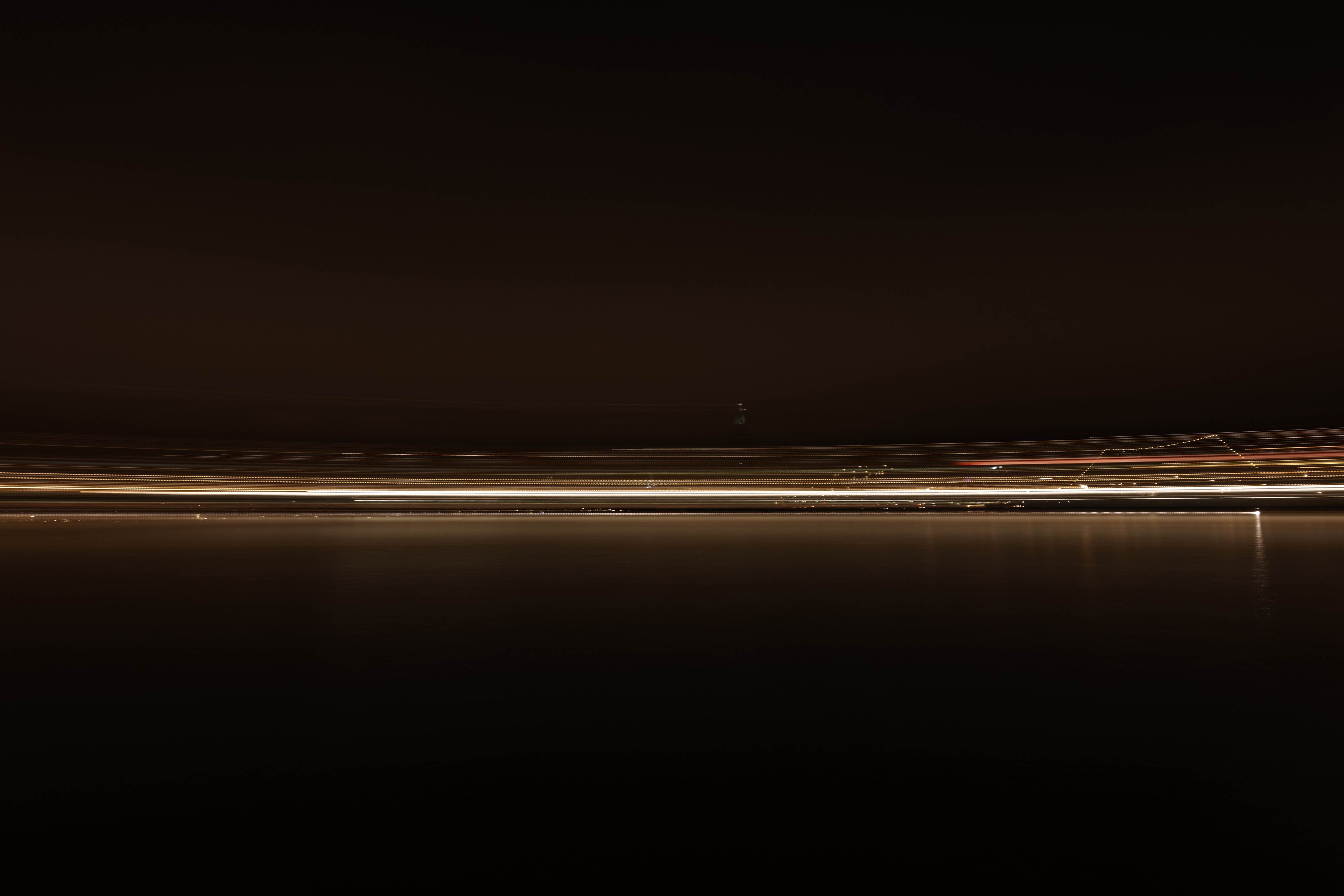 Long exposure of city lights reflecting on water at night HD Wallpaper