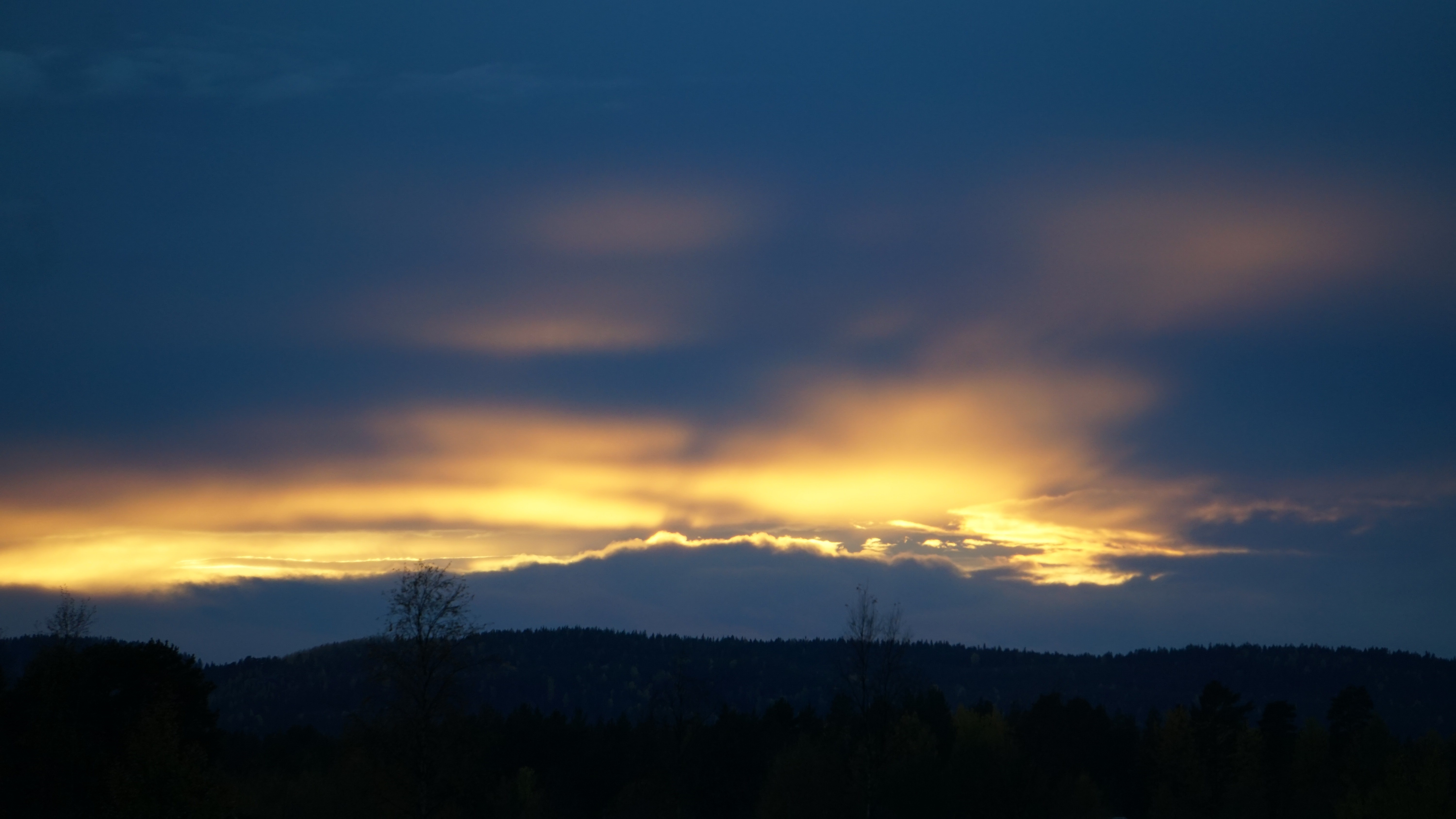 Sunset over a dark forest and hills HD Wallpaper