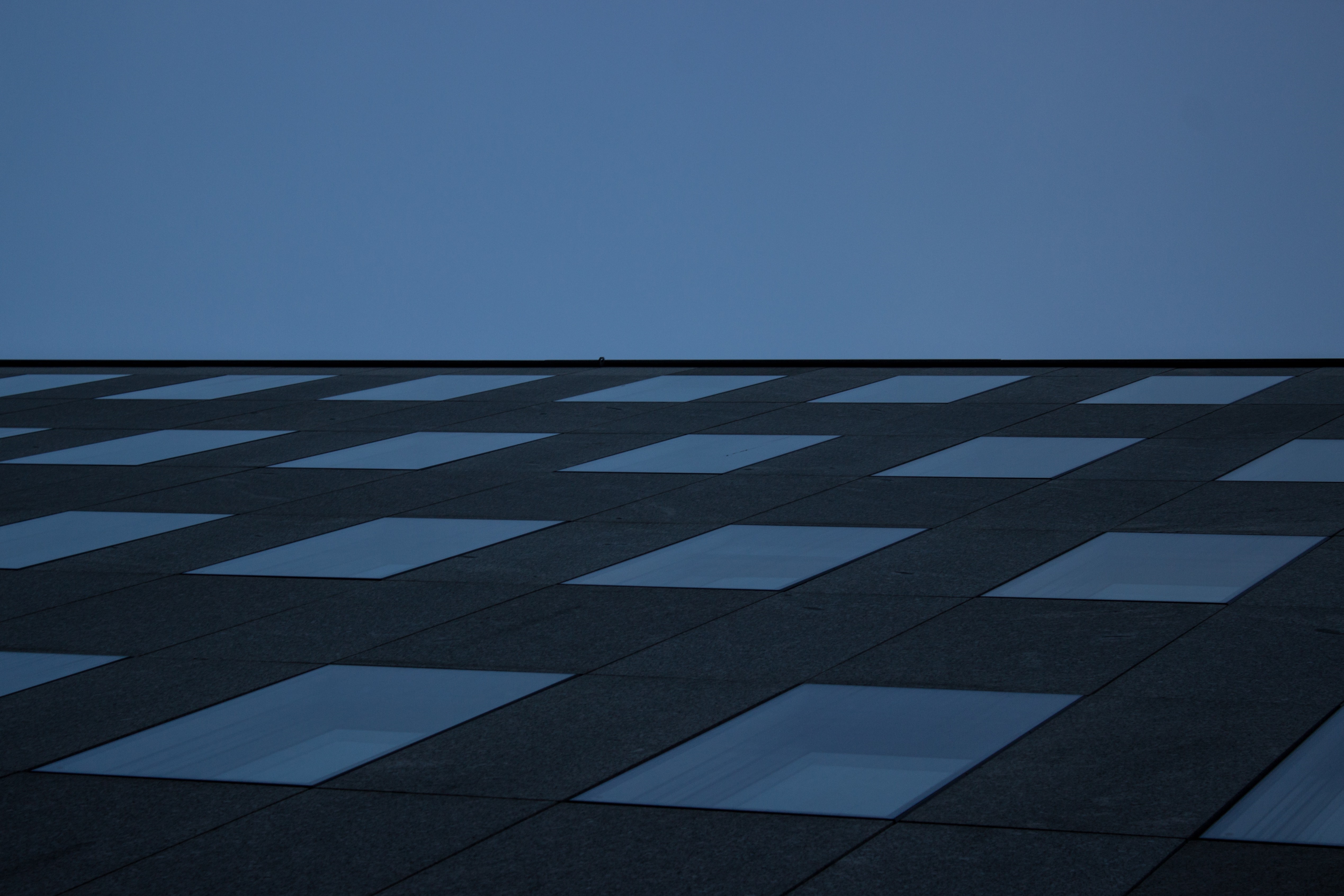 Modern building facade with repeating windows against blue sky HD Wallpaper