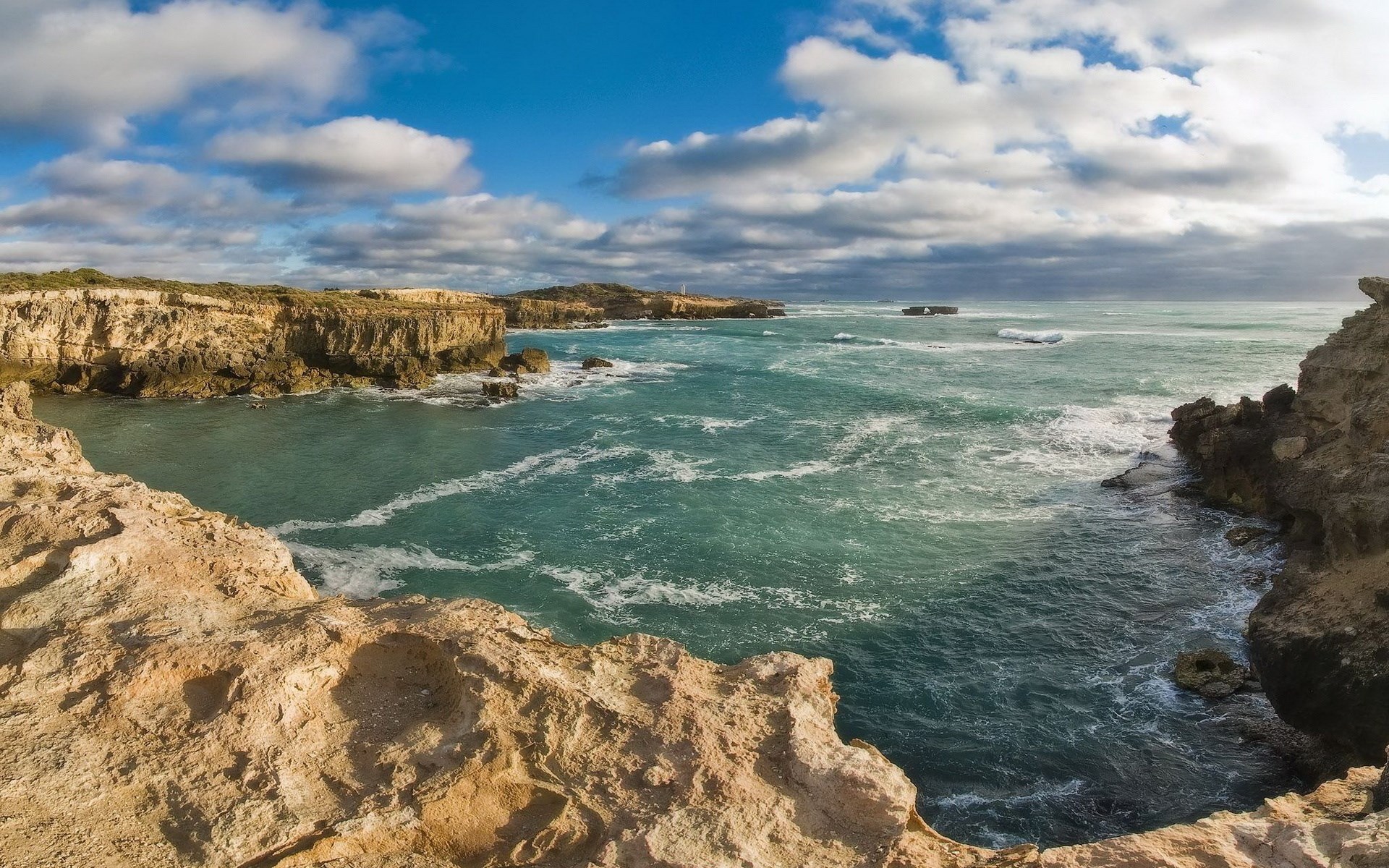 Rocky coastline with turquoise ocean and cloudy sky HD Wallpaper