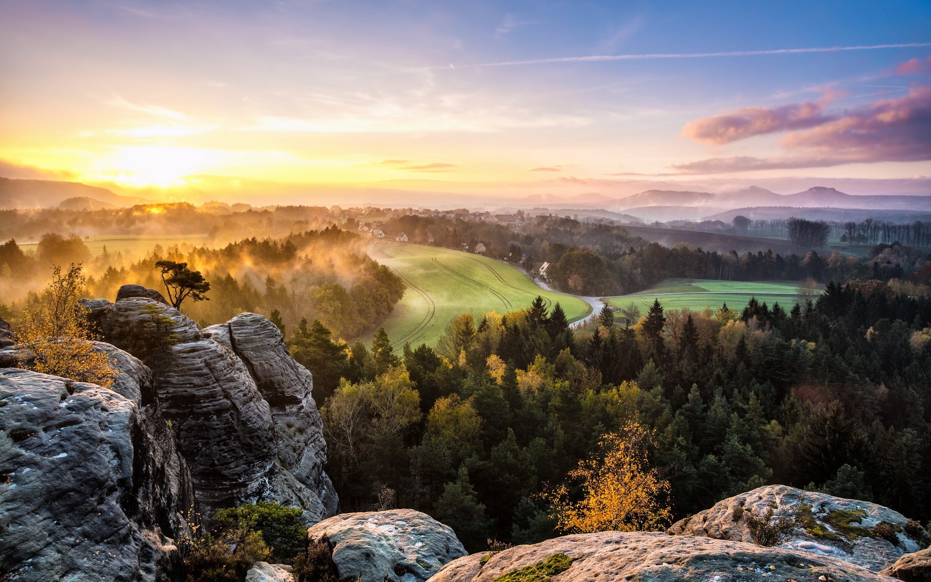 Misty sunrise over a forested valley with rock formations HD Wallpaper