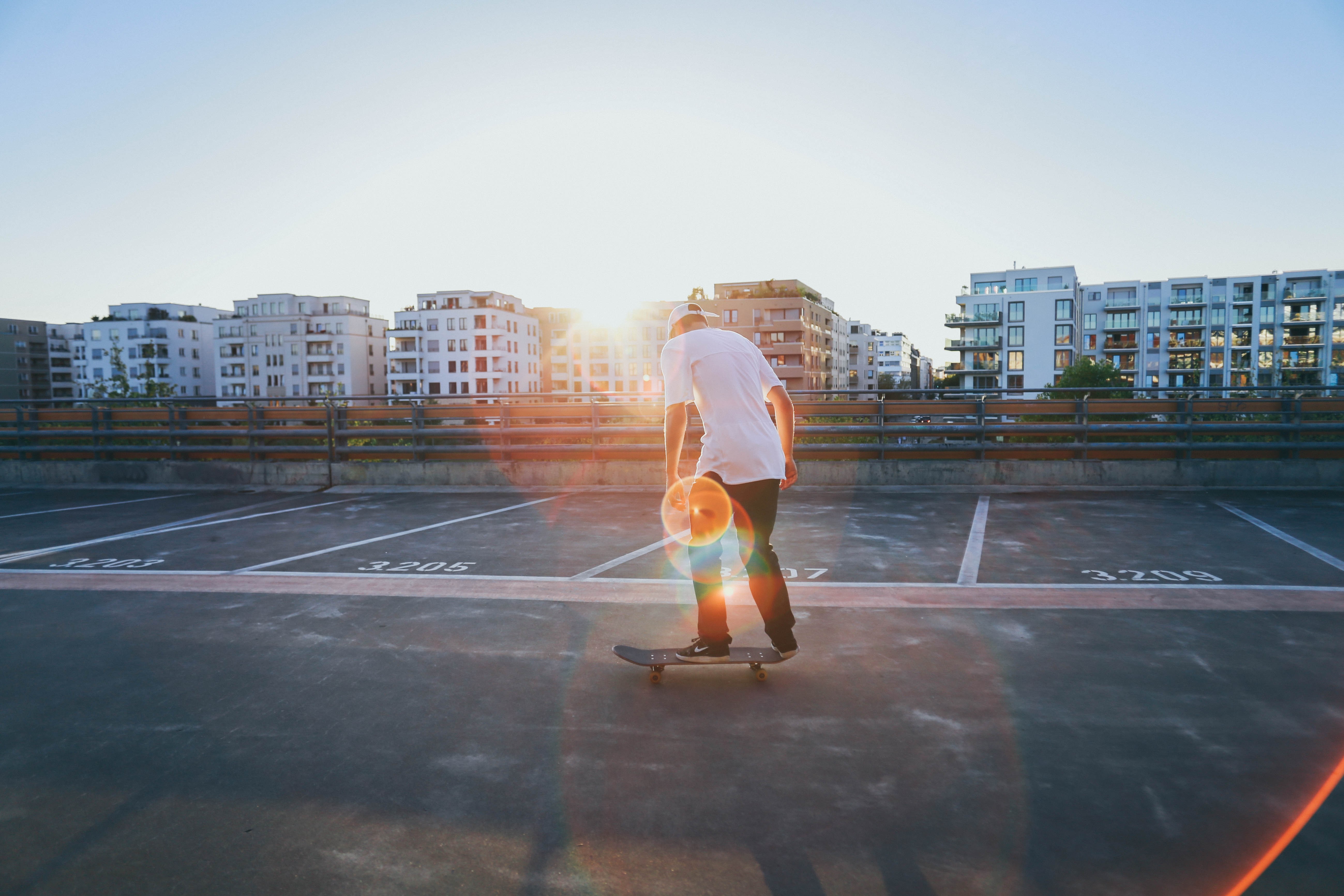 Skateboarder on rooftop parking lot at sunset HD Wallpaper